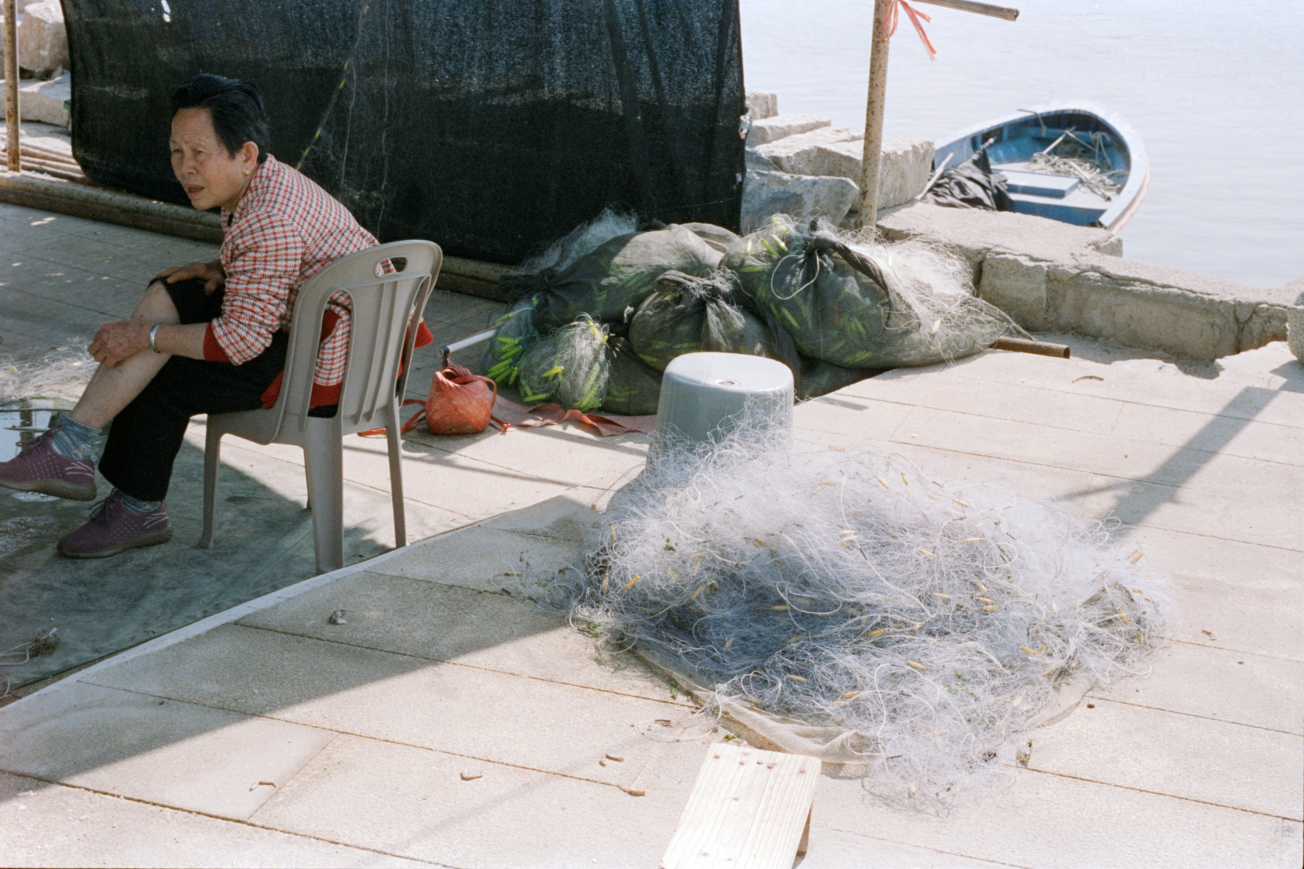 Woman sitting by fishing nets near water