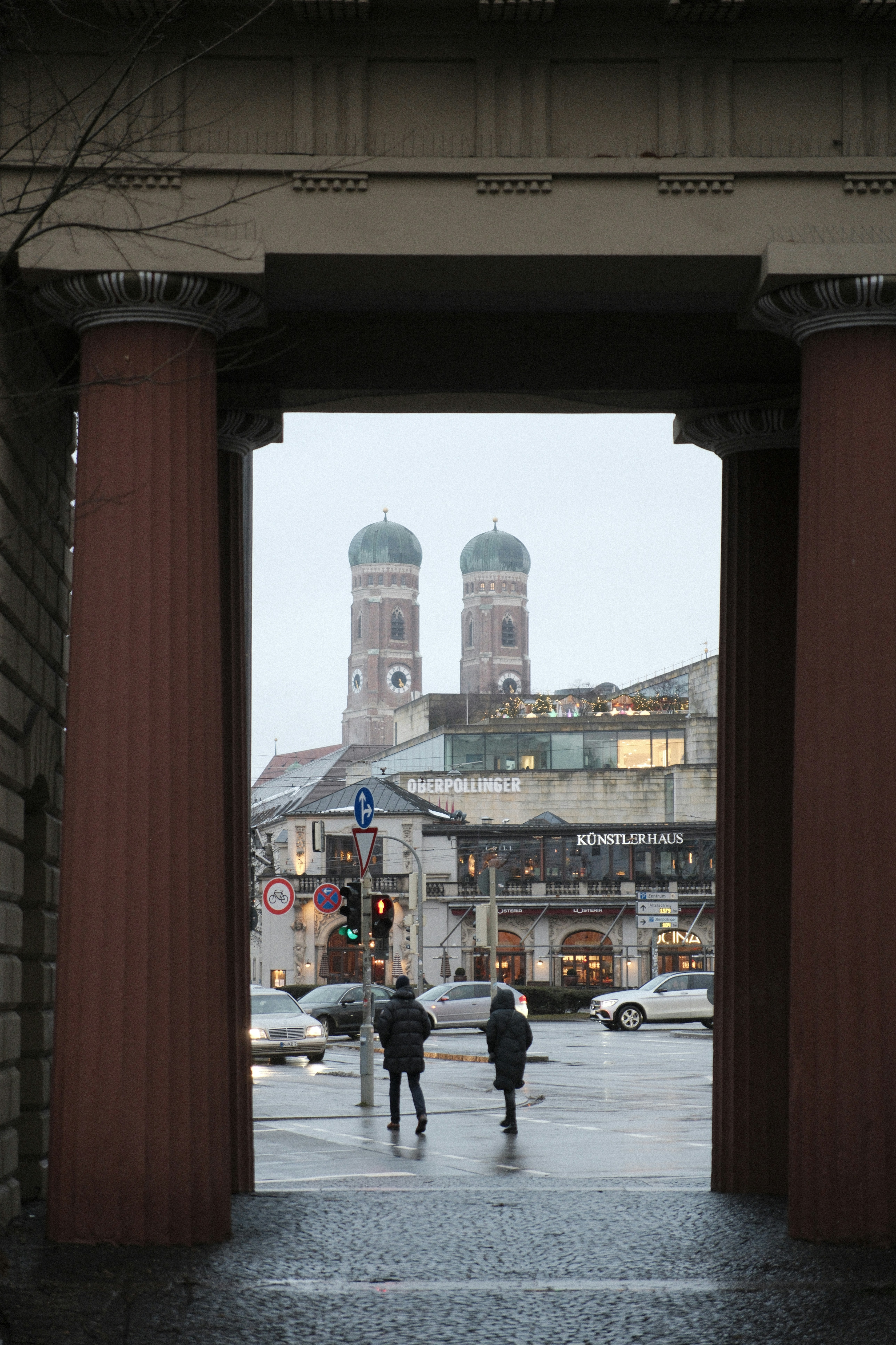 Two towers framed by large columns with city street below.