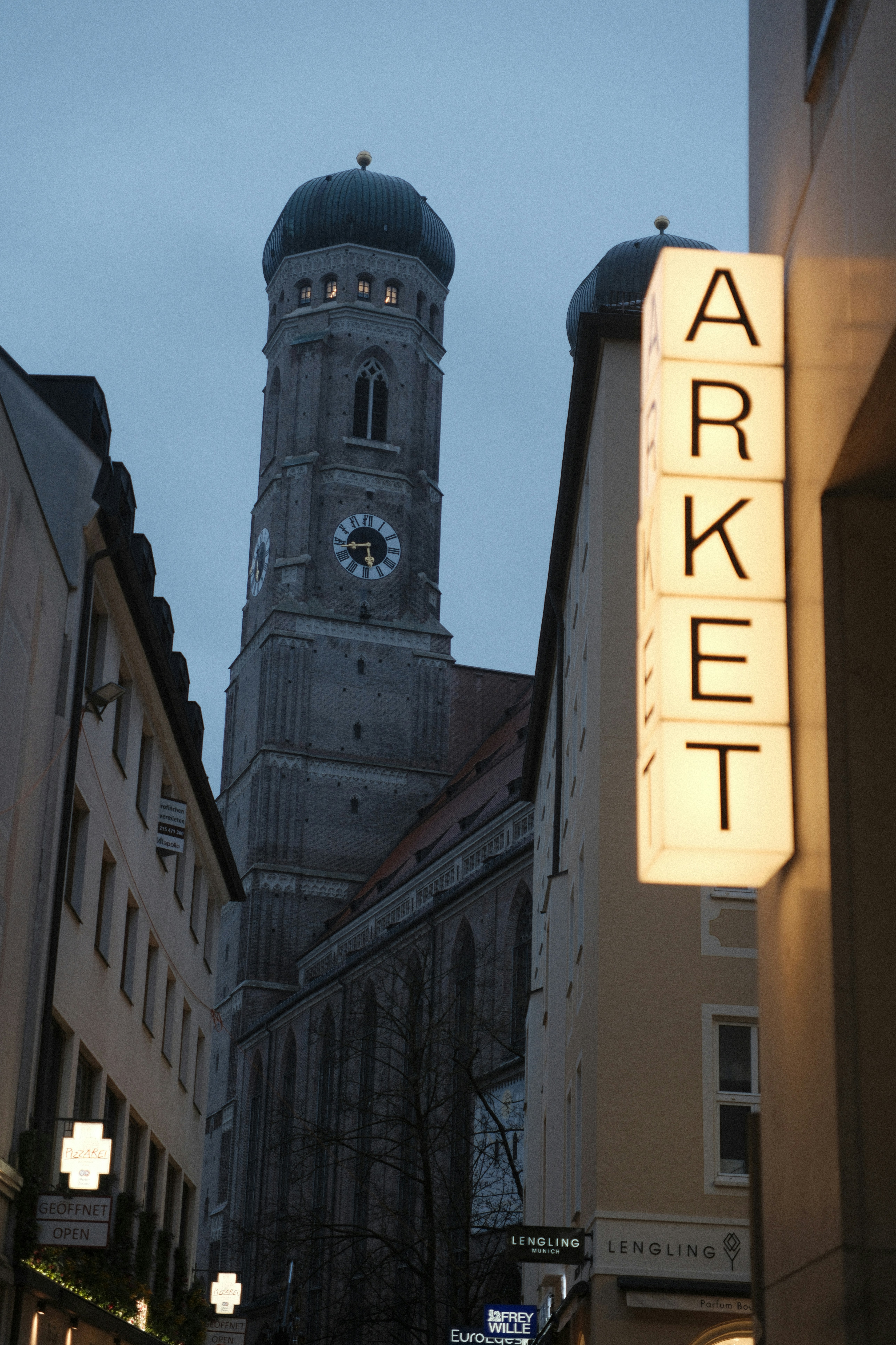 A tall church tower looms over a narrow street.