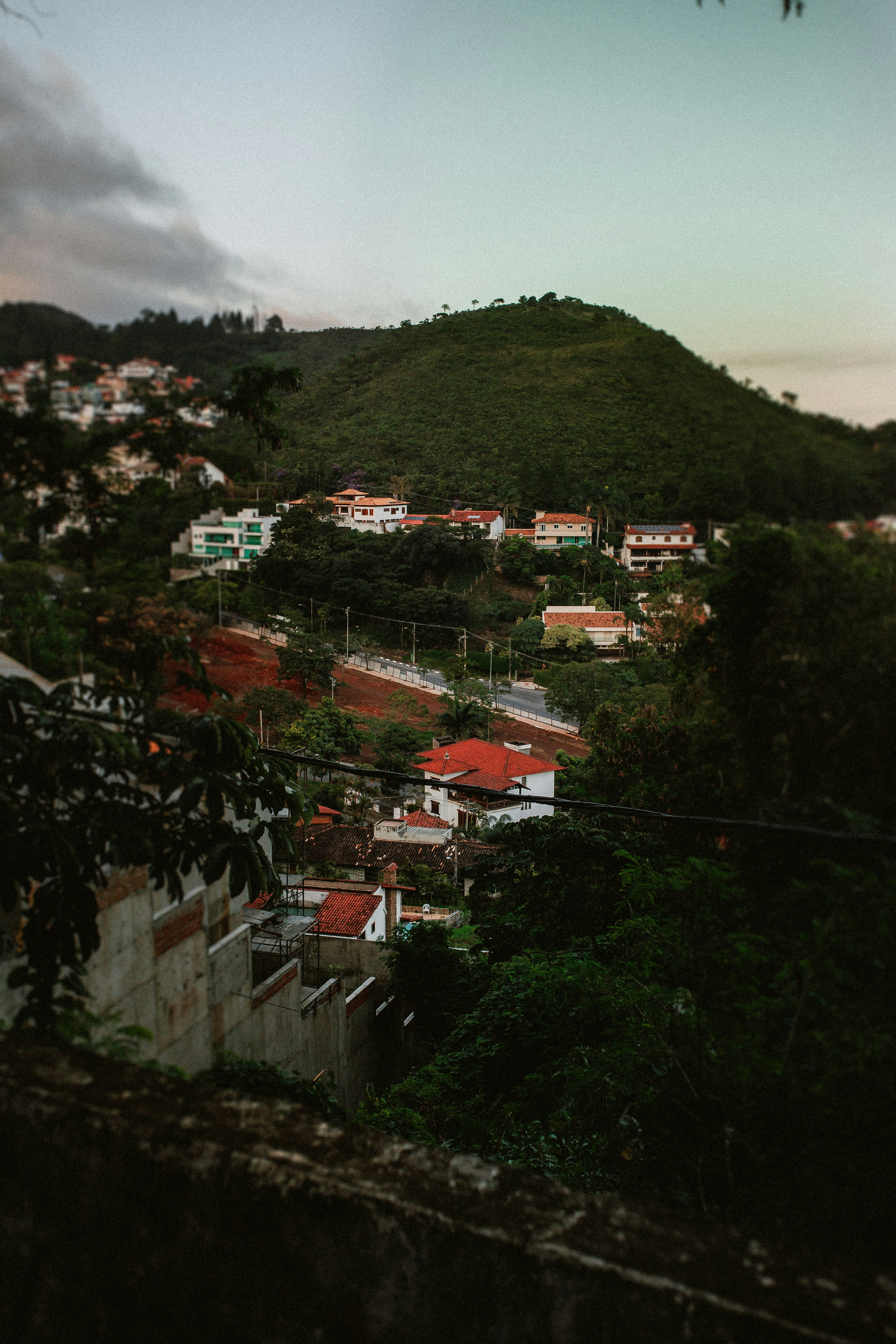 Häuser, eingebettet an einem grünen Hang in der Dämmerung.
