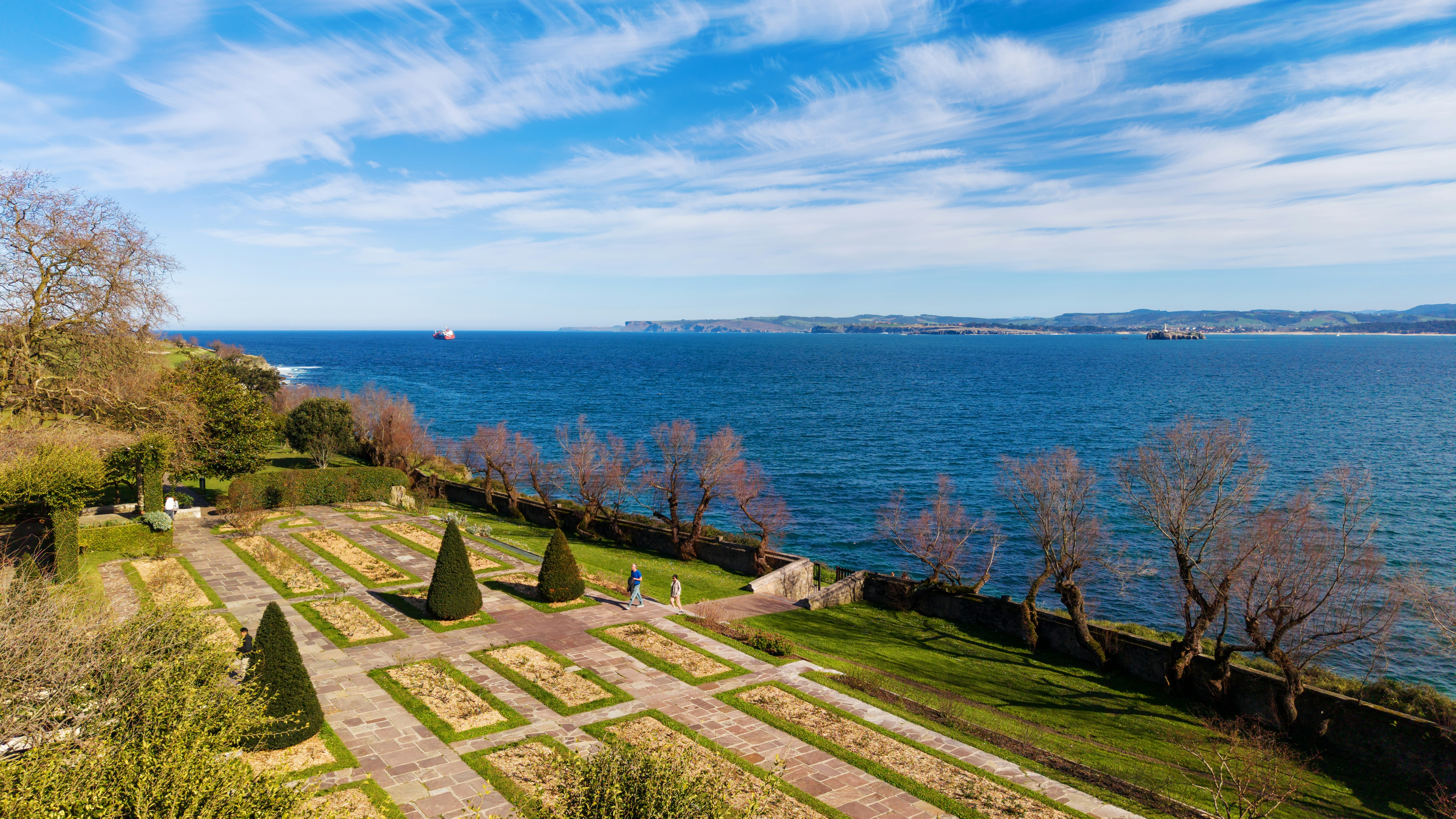 Formal garden overlooking a wide blue ocean under sky