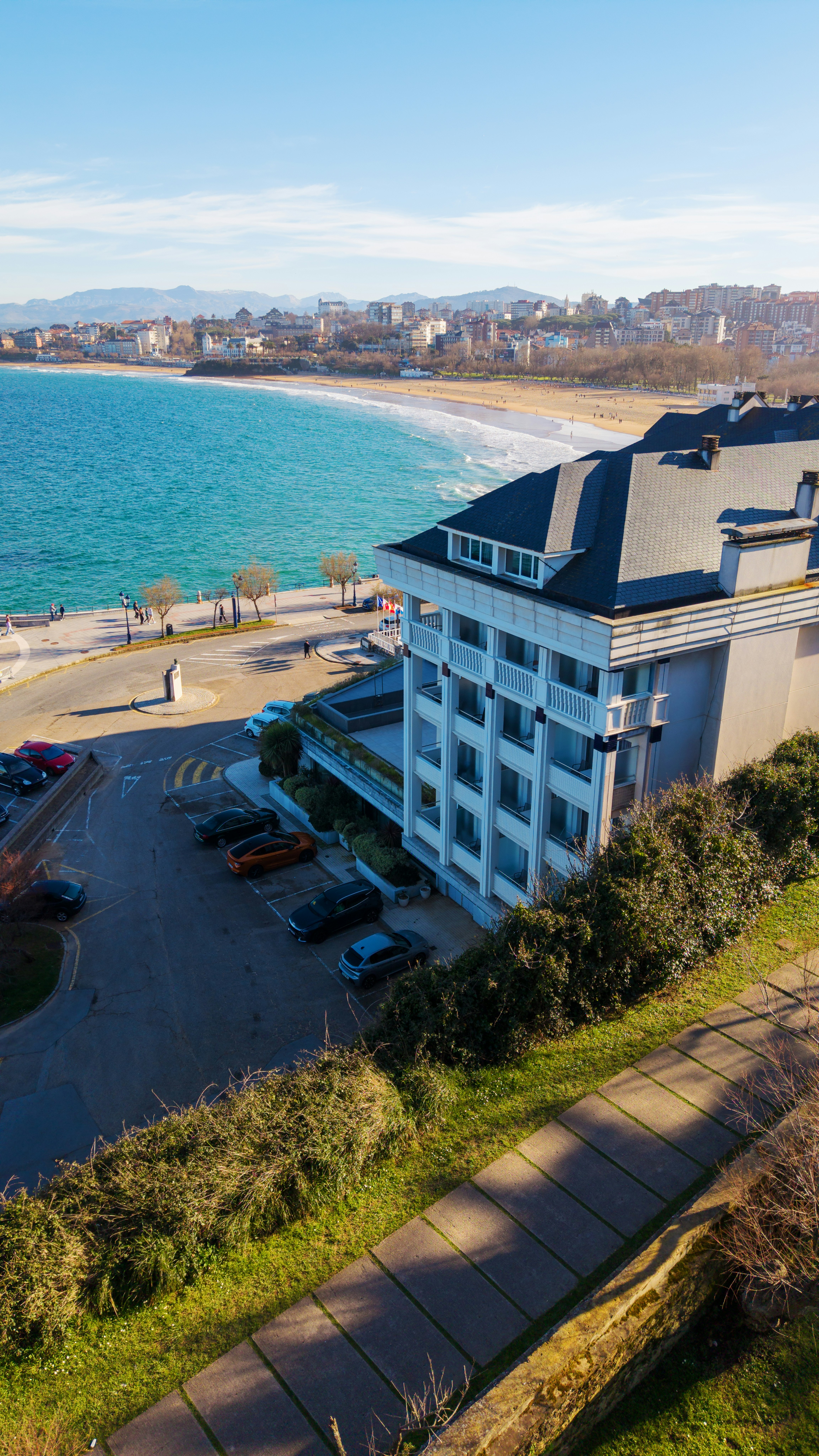 Modern hotel overlooking a sandy beach and turquoise ocean.