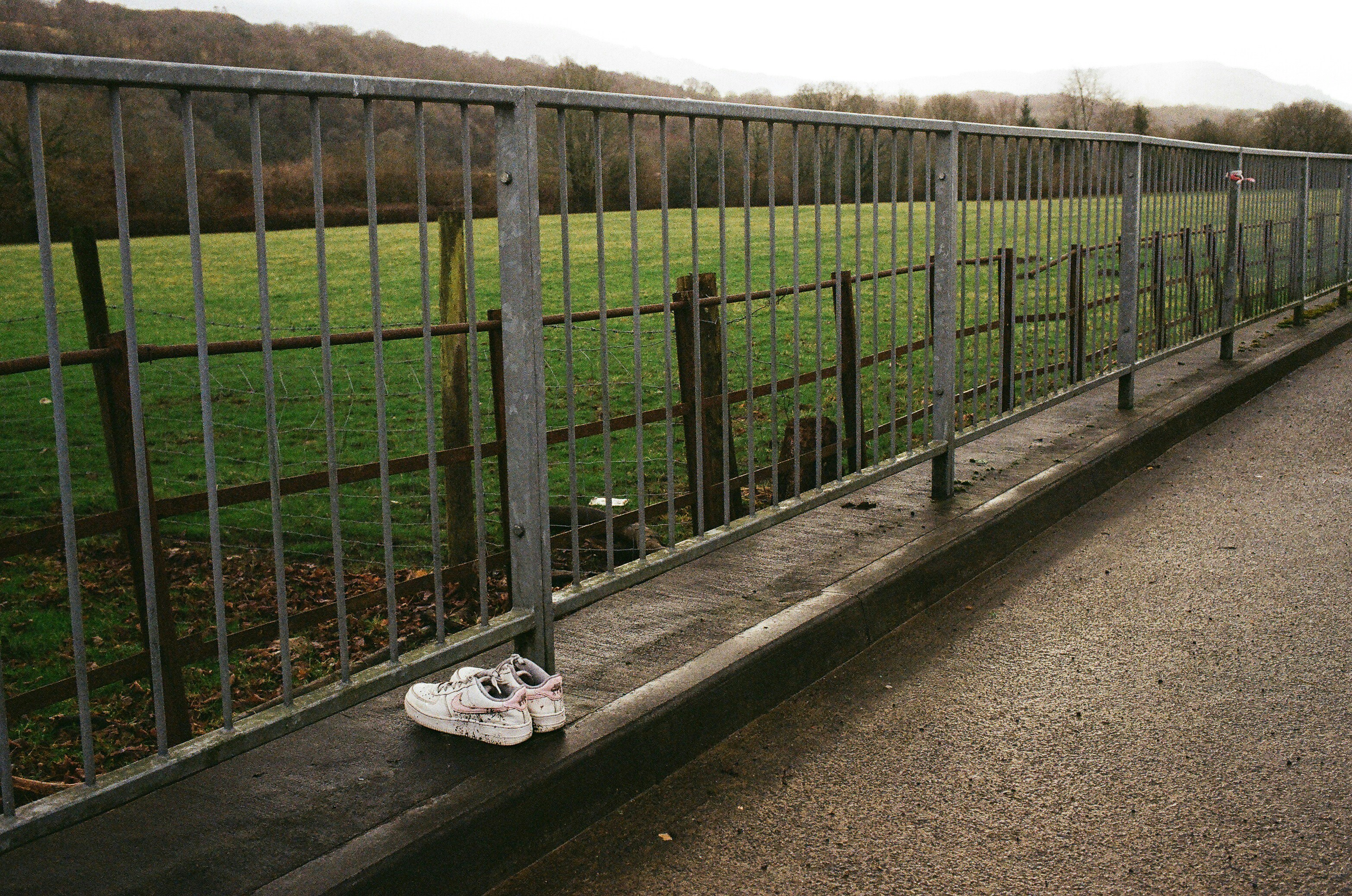 A pair of white sneakers rests on a metal railing.