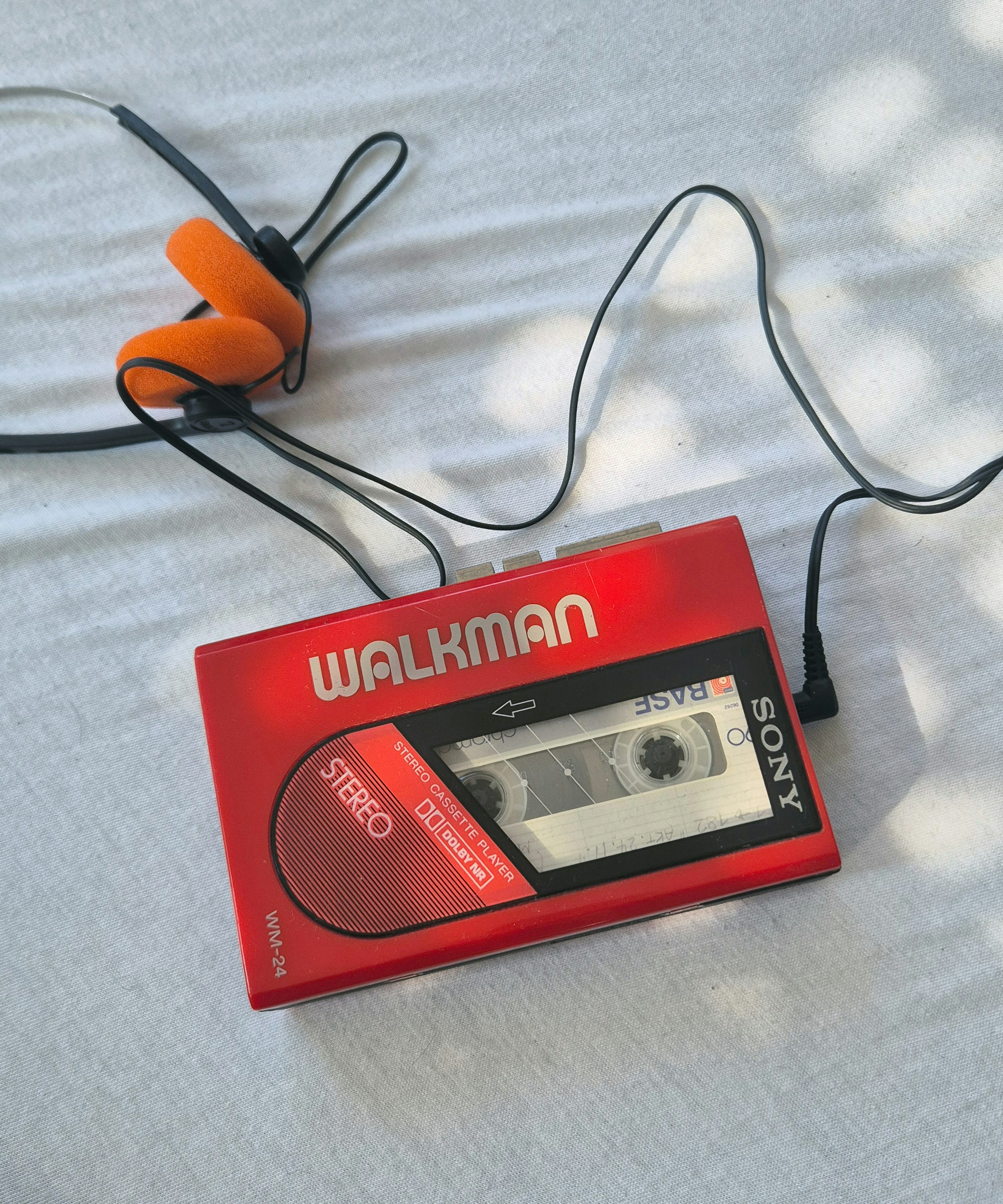 Walkman sony merah dengan earbud oranye headphone on-ear