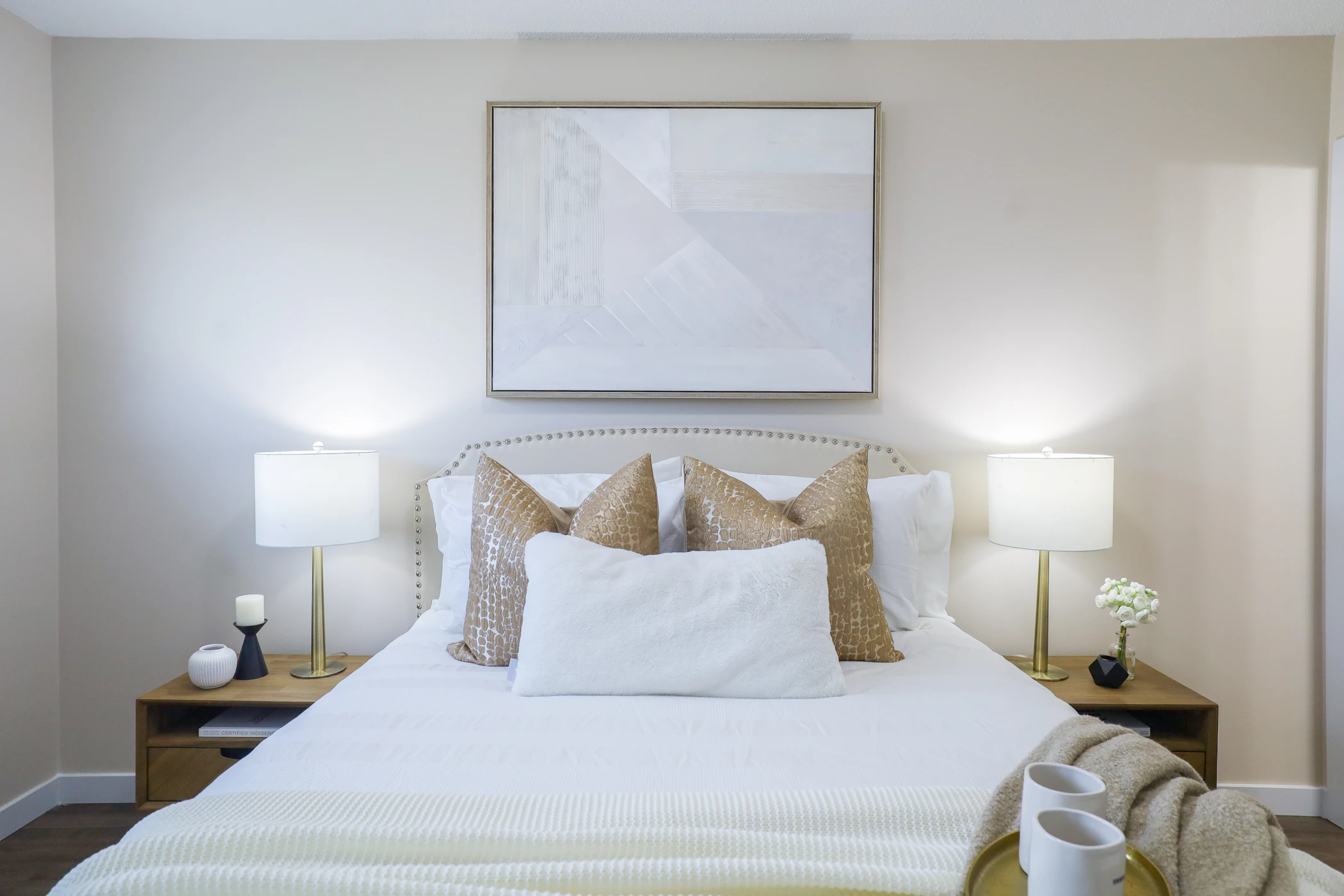 Calm bedroom interior with bed, bedside tables, lamps and neutral decorative details