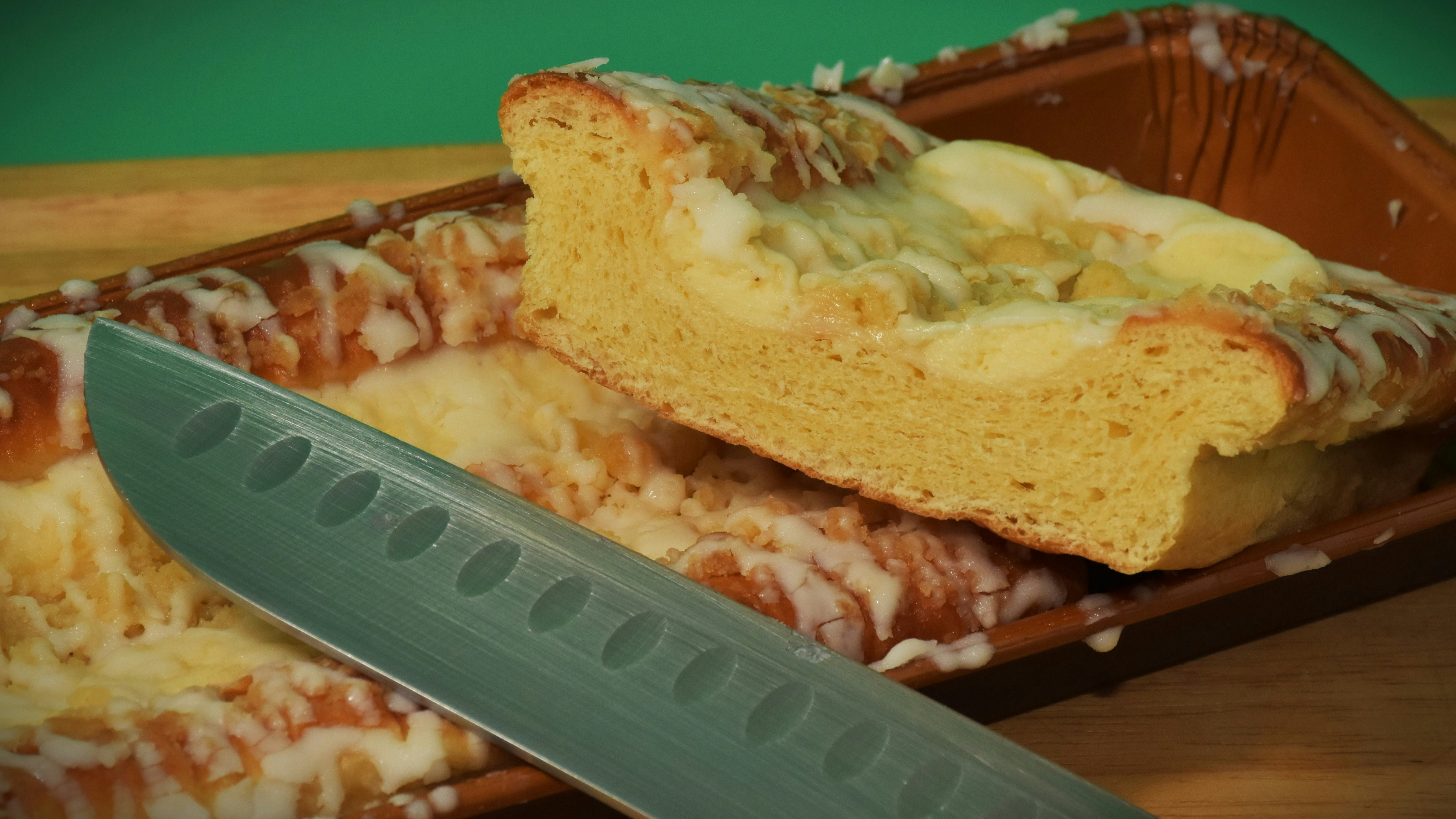A loaf of bread with icing and a knife.
