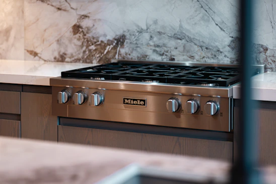 Modern stainless steel gas range with marble backsplash