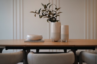 Two vases and a bowl on a wooden table.