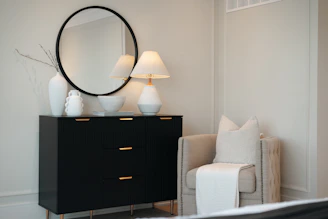 Black dresser with mirror and chair in a bedroom