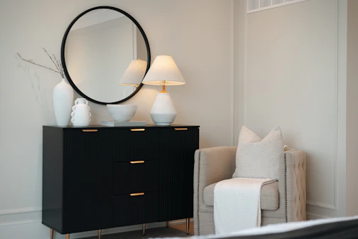 Black dresser with mirror and chair in a bedroom