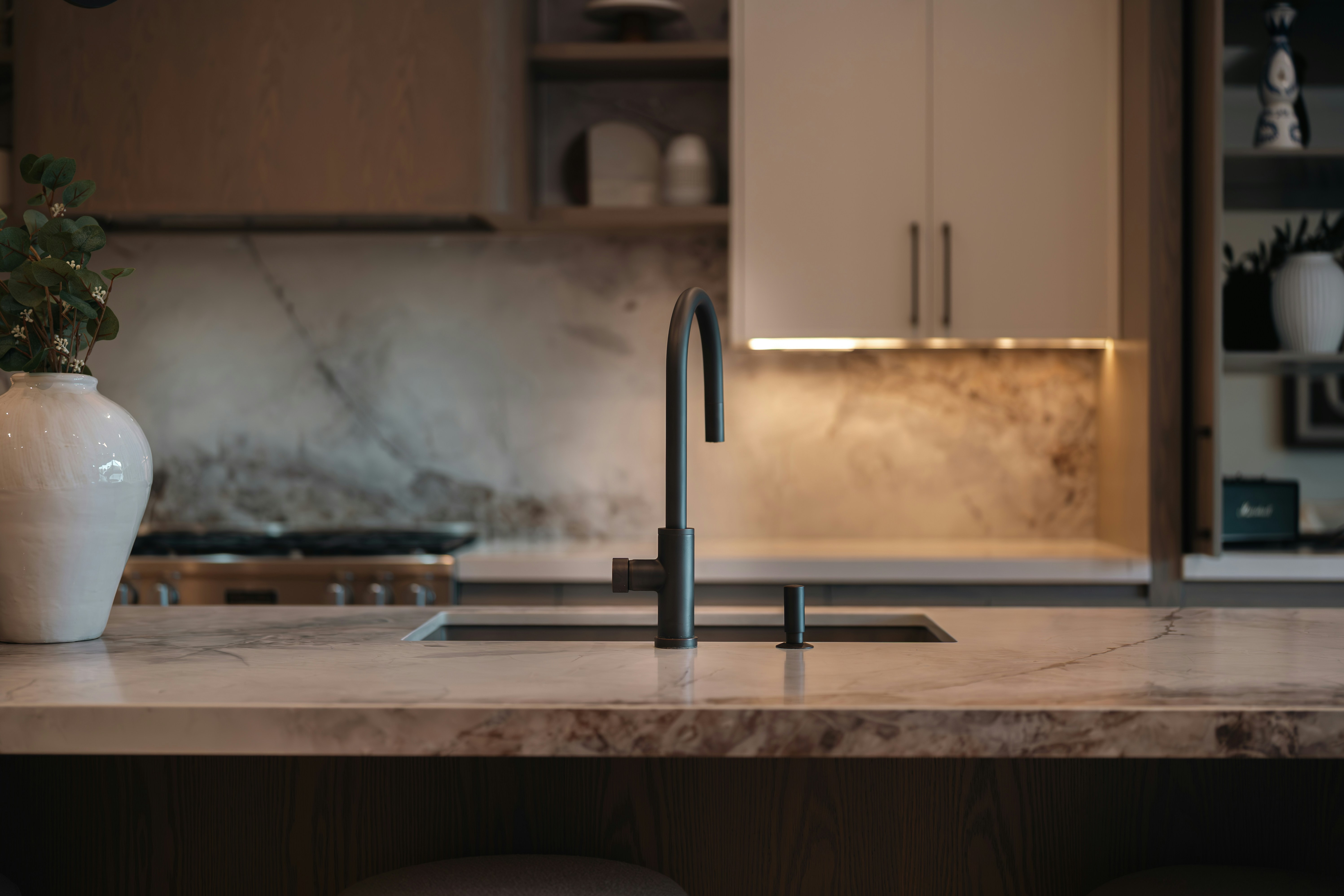 Modern kitchen sink with marble countertop and backsplash.