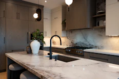 Modern kitchen with marble island and dark faucet.