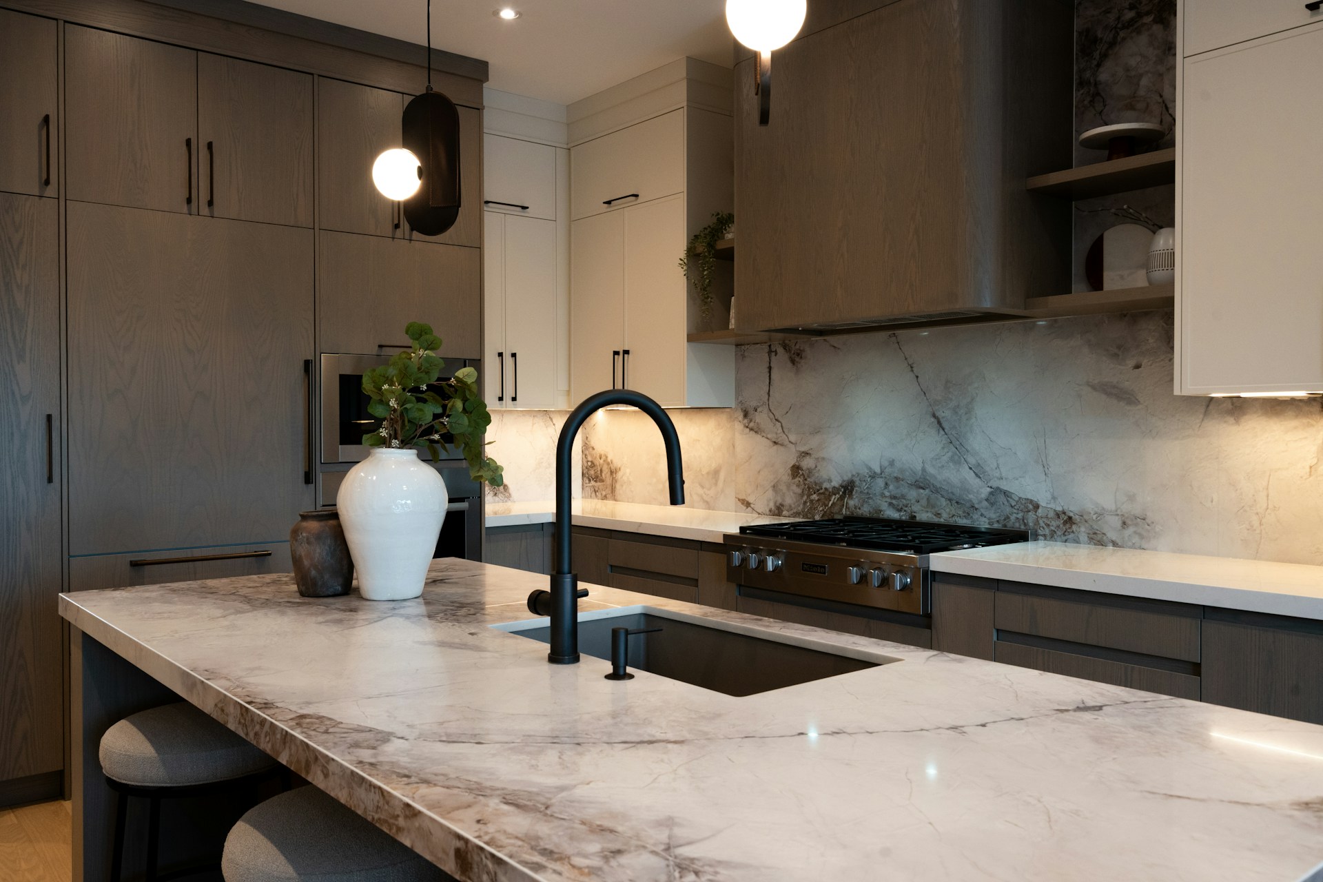 Modern kitchen with marble island and dark faucet.