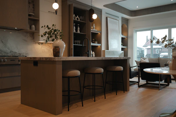 Modern kitchen island with stools and living area view.