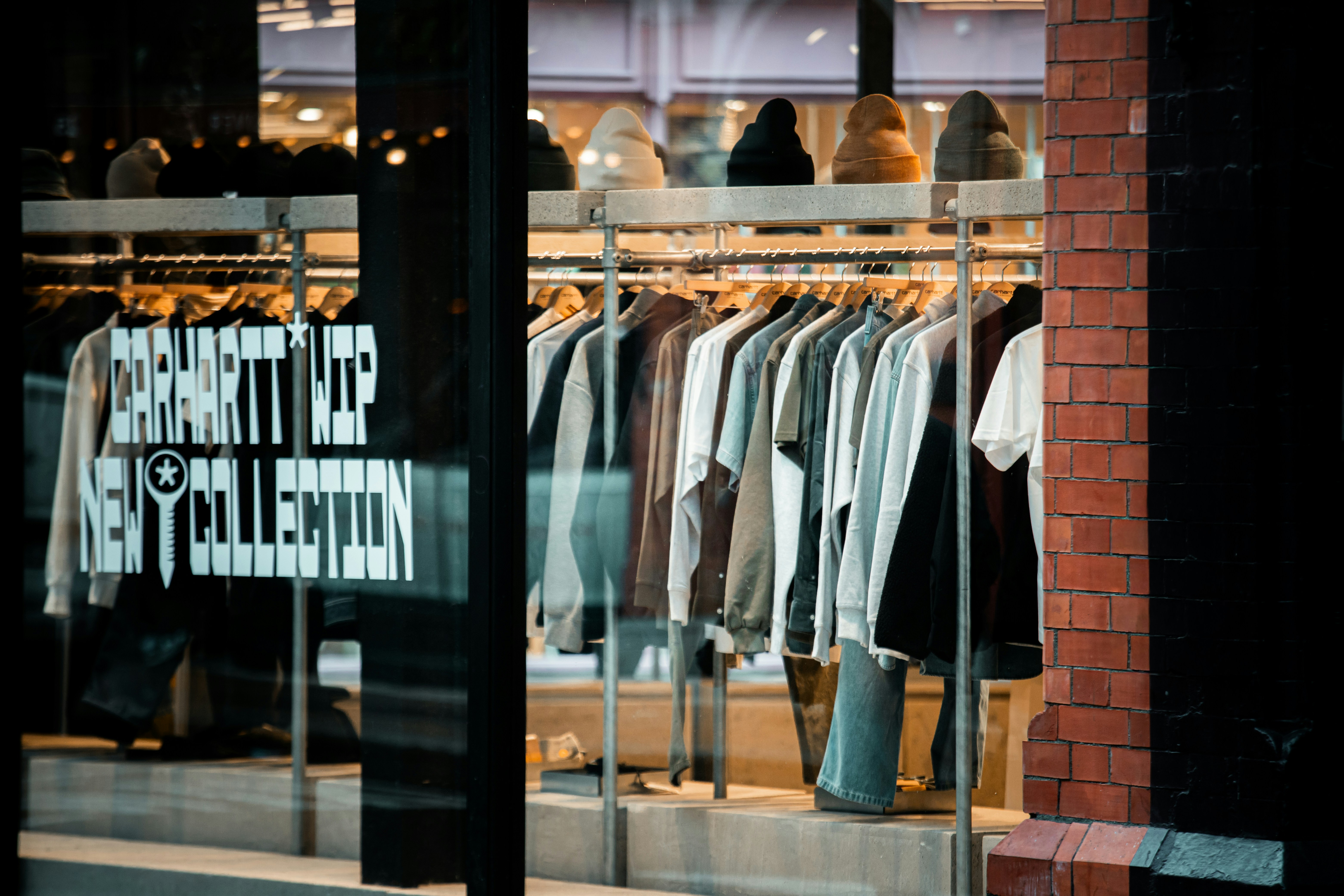 Clothes displayed on racks inside a window.