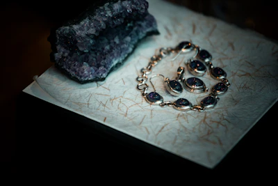 Amethyst jewelry and raw crystal on textured paper
