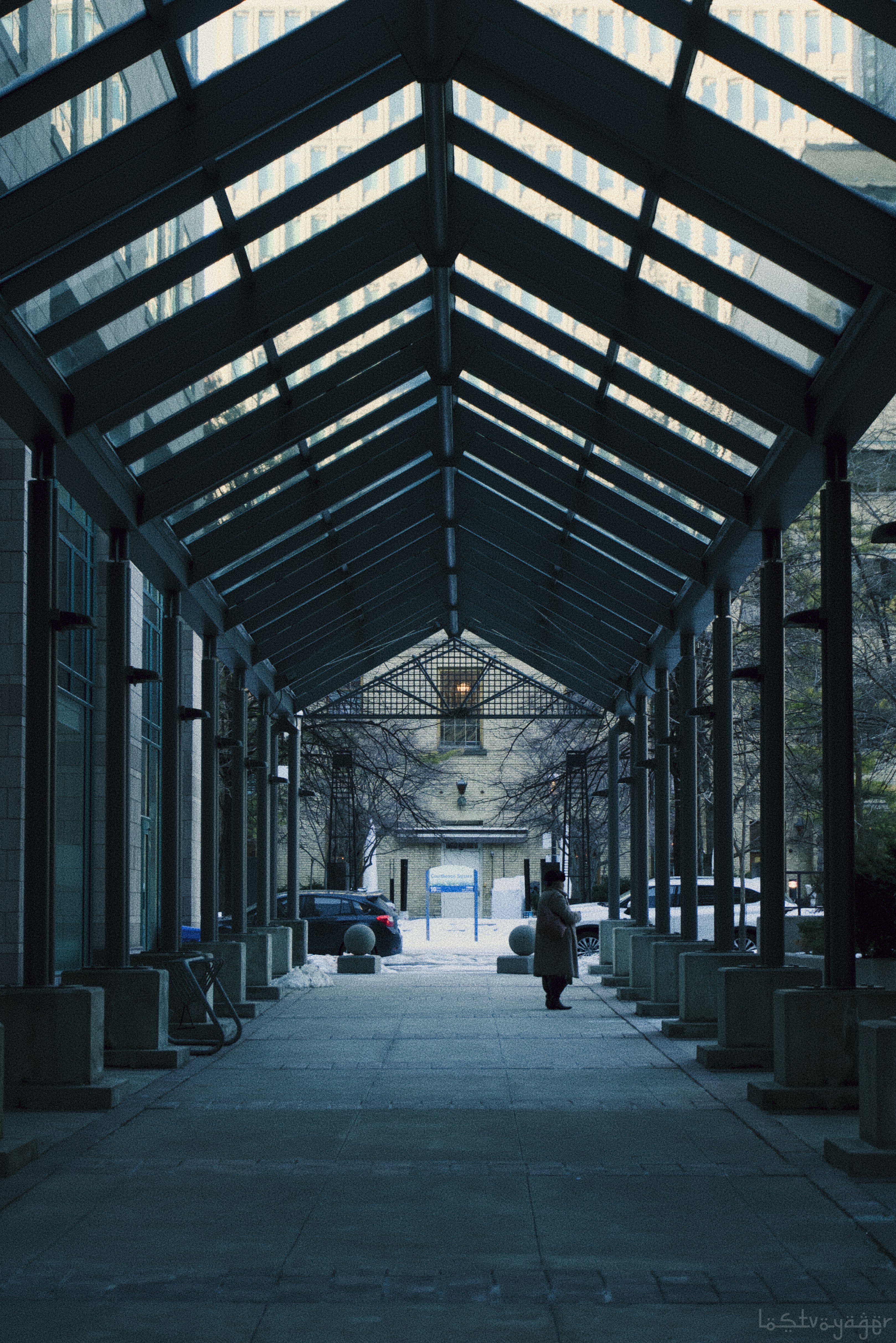 Una persona camina por un pasillo cubierto con techo de cristal.