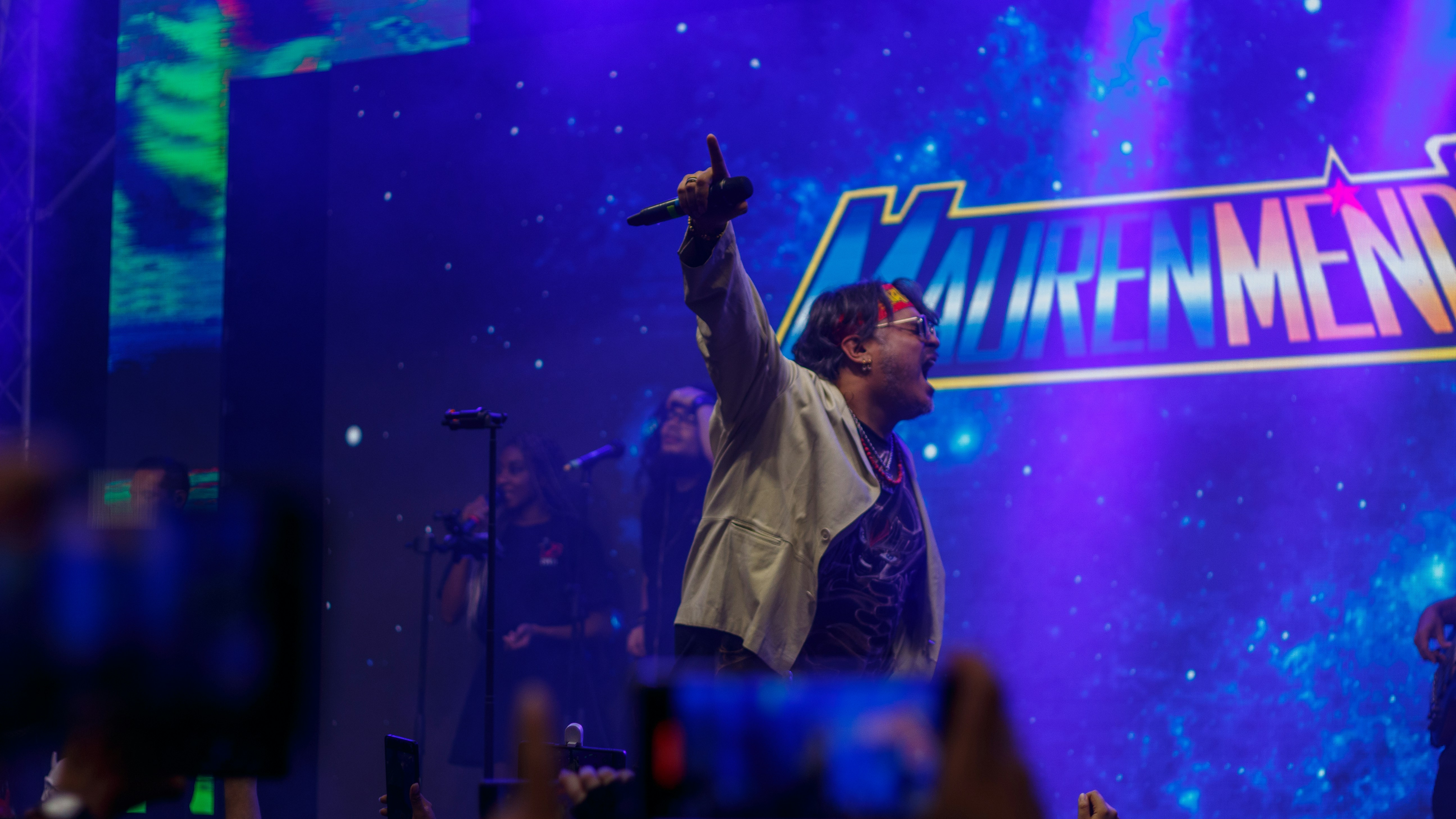 Singer performing on stage with crowd holding phones