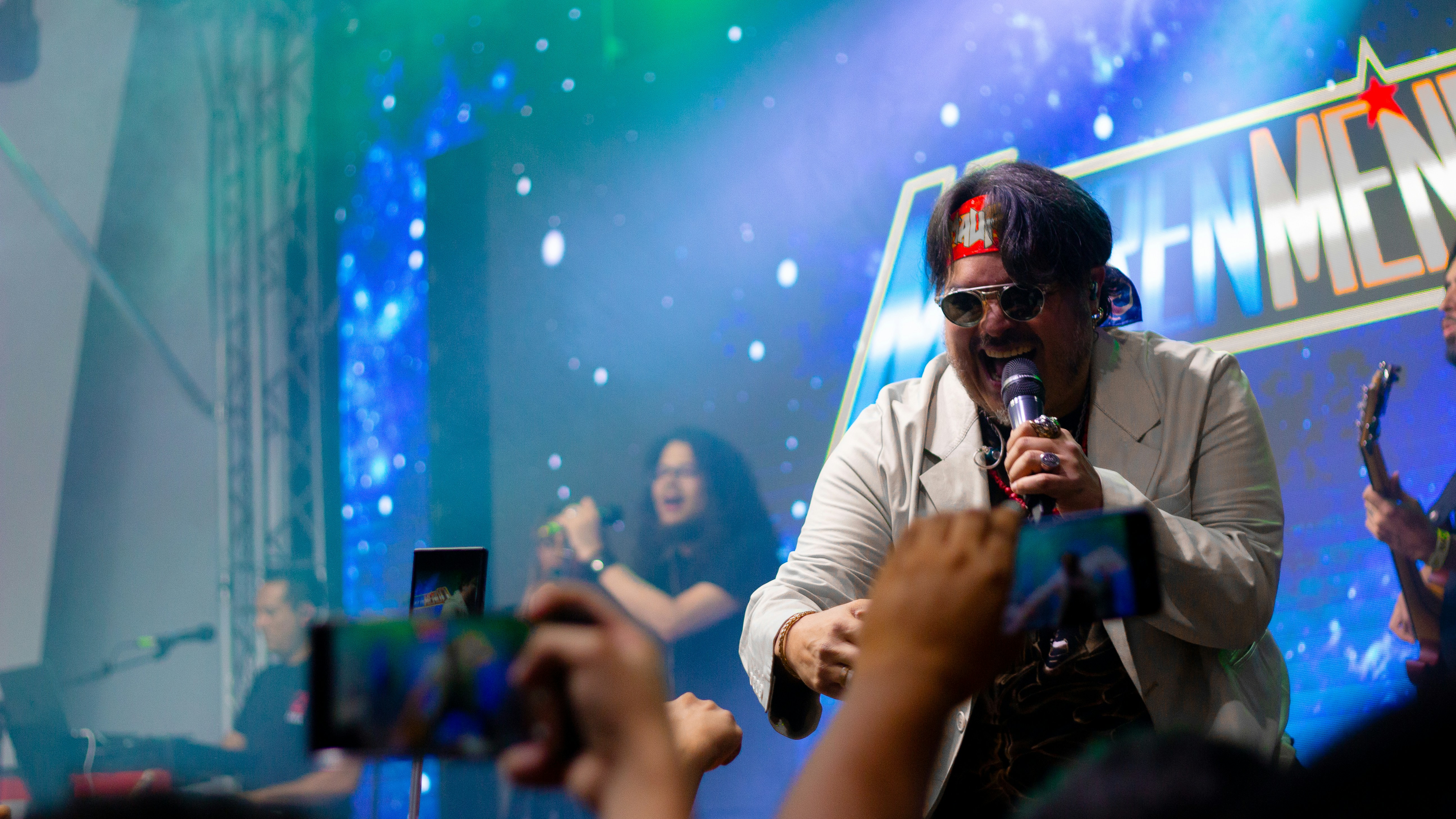 A band performs on stage with a cheering crowd.