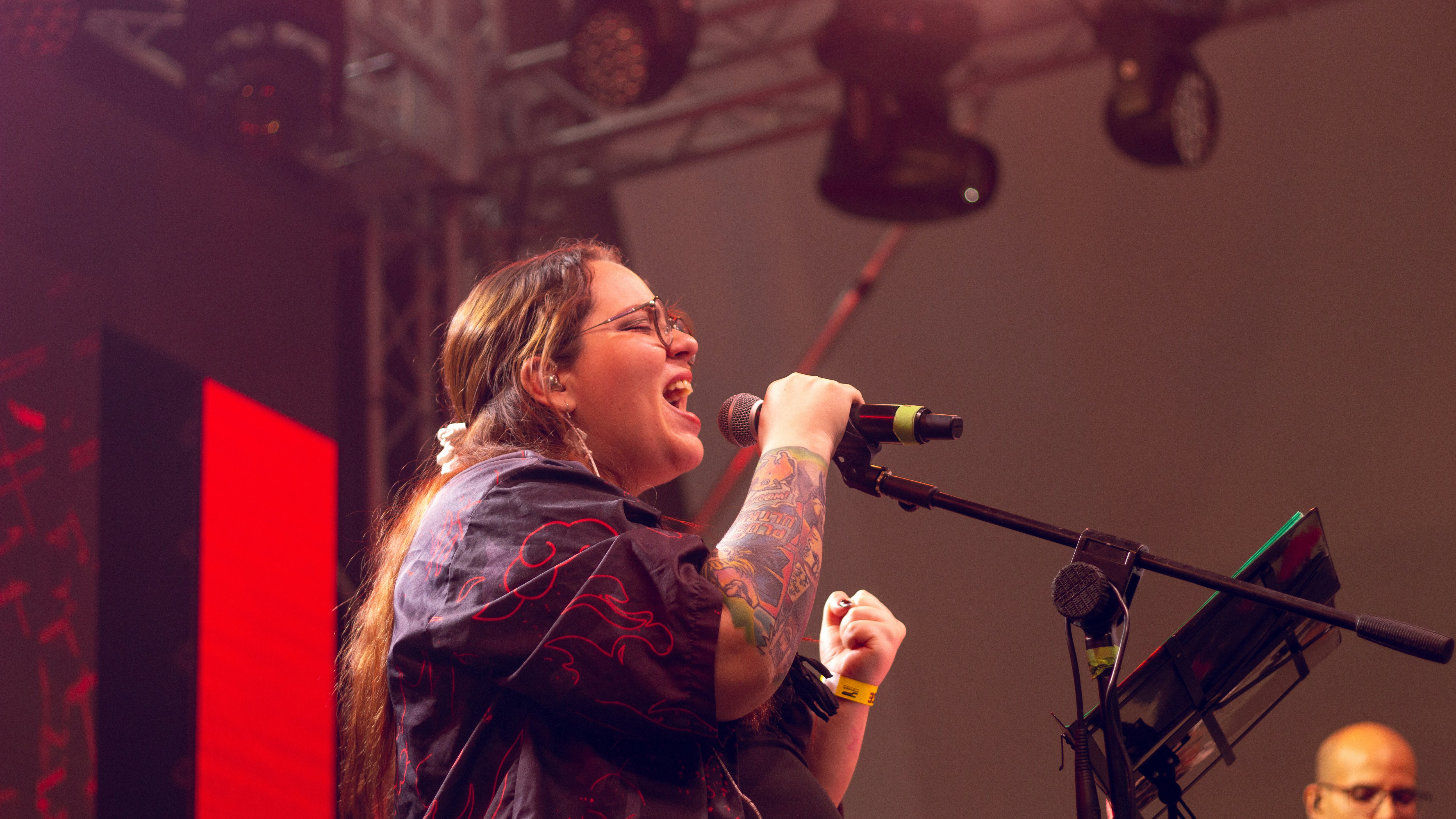 Una mujer cantando apasionadamente en un micrófono en el escenario.