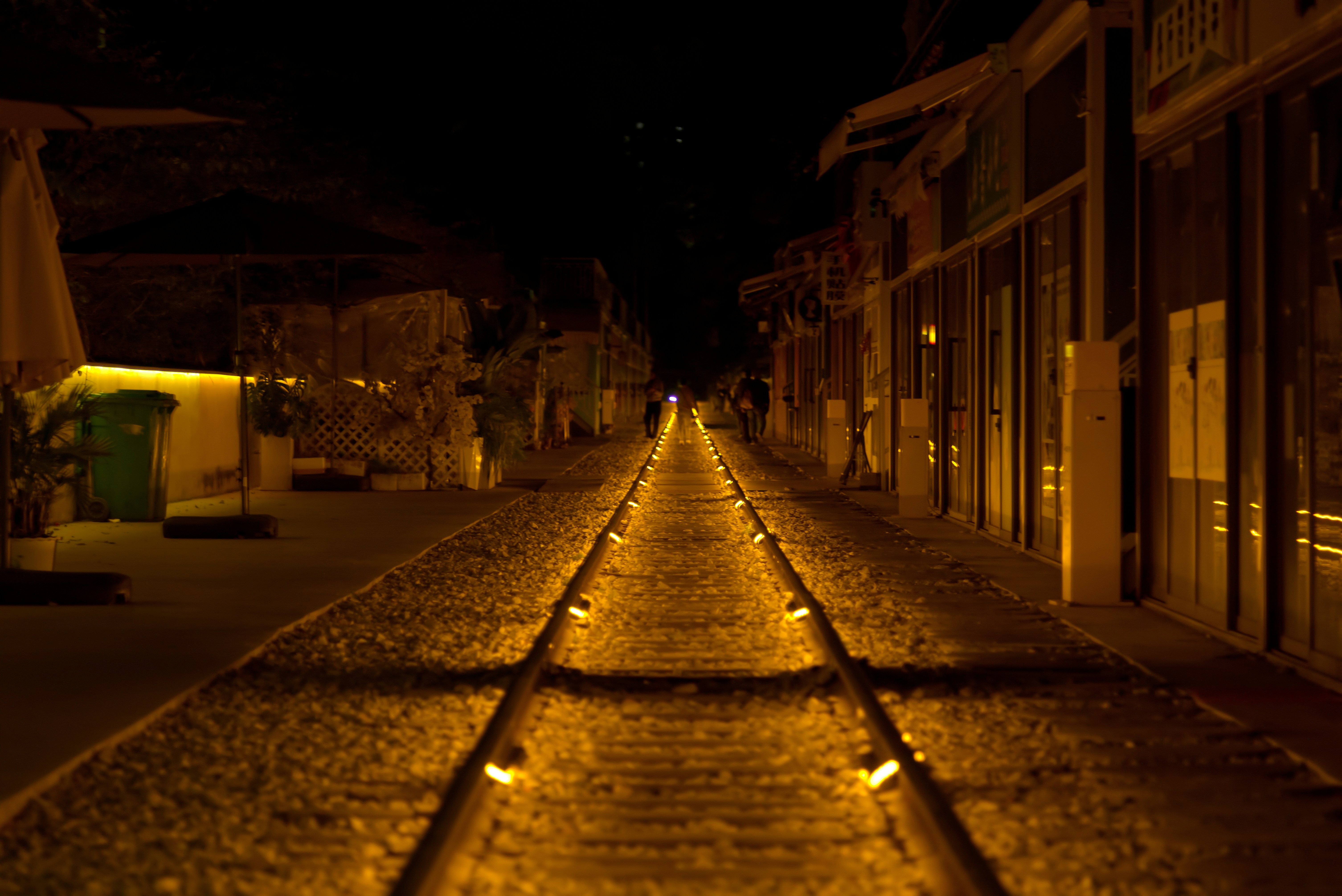 Trilhos de trem iluminados à noite com luzes quentes.