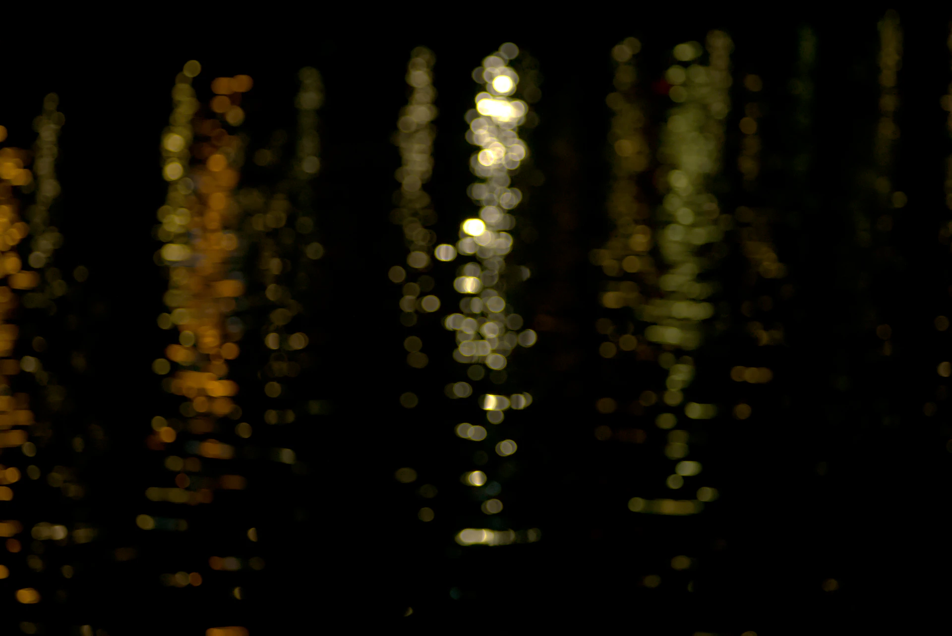 Bokeh lights reflecting on dark water at night