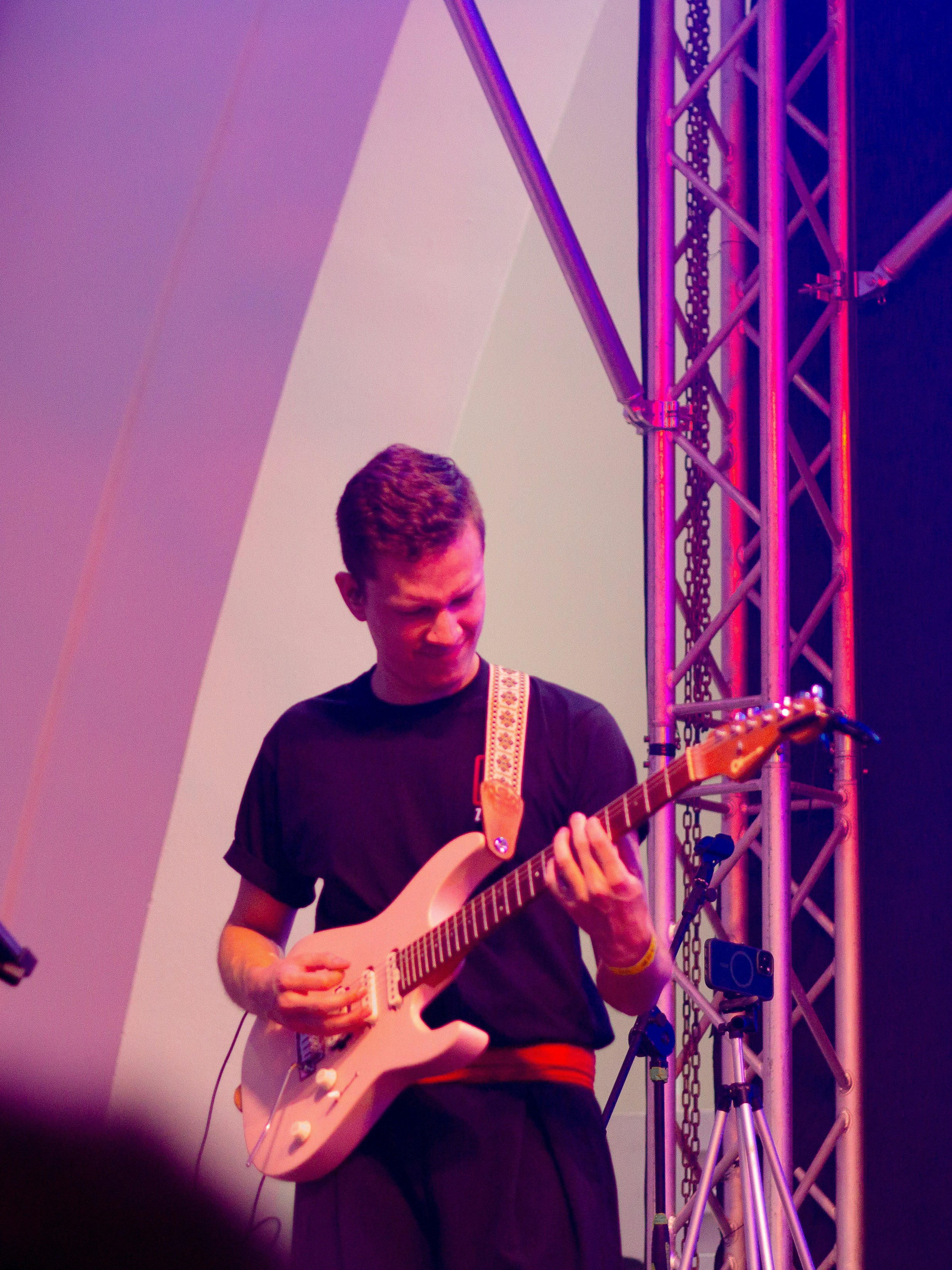 Man playing a pink electric guitar on stage
