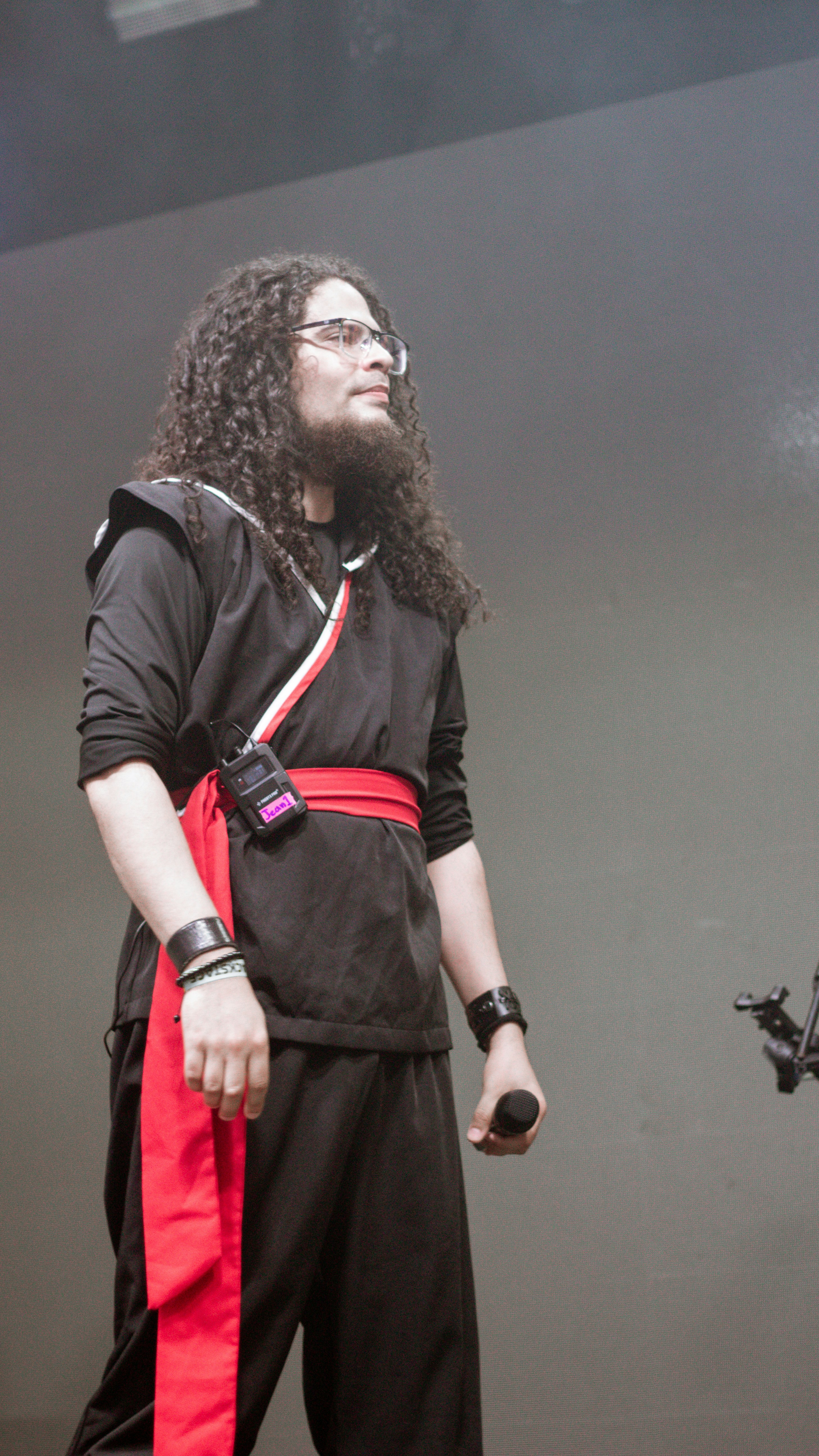 黒と赤の服を着た長い巻き毛の男性