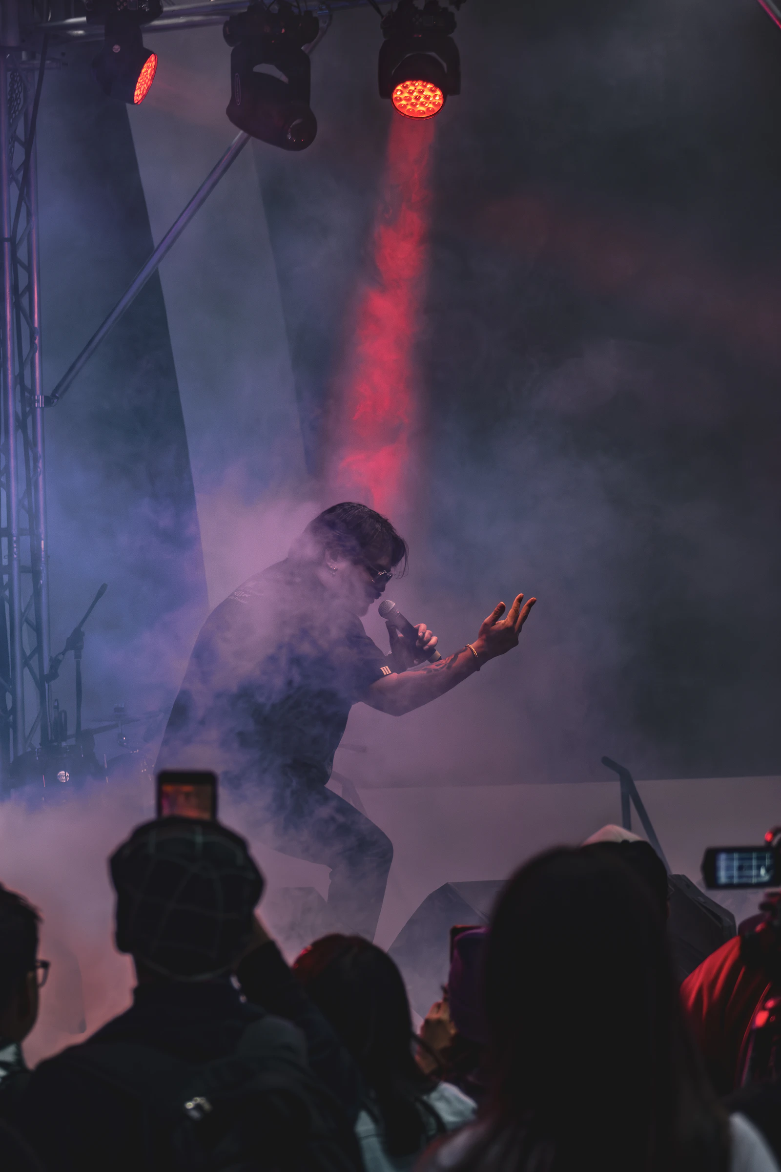 Singer performing on a smoky stage under a red spotlight