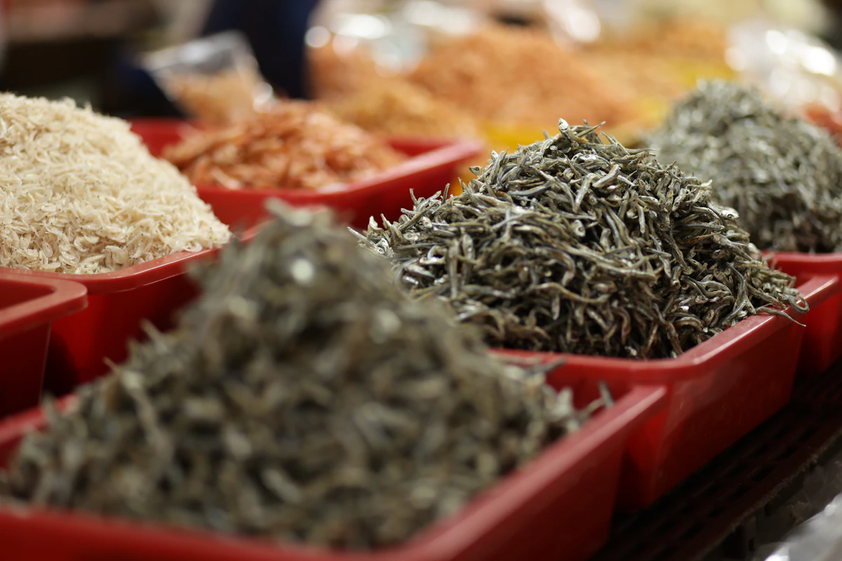 Small dried fish displayed in red containers at a market