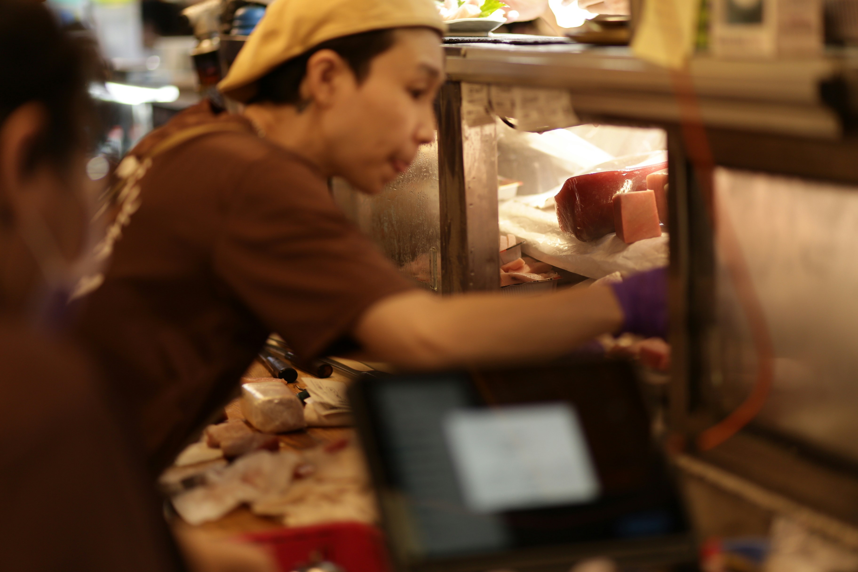 帽子をかぶった人物が展示ケースに手を伸ばす。