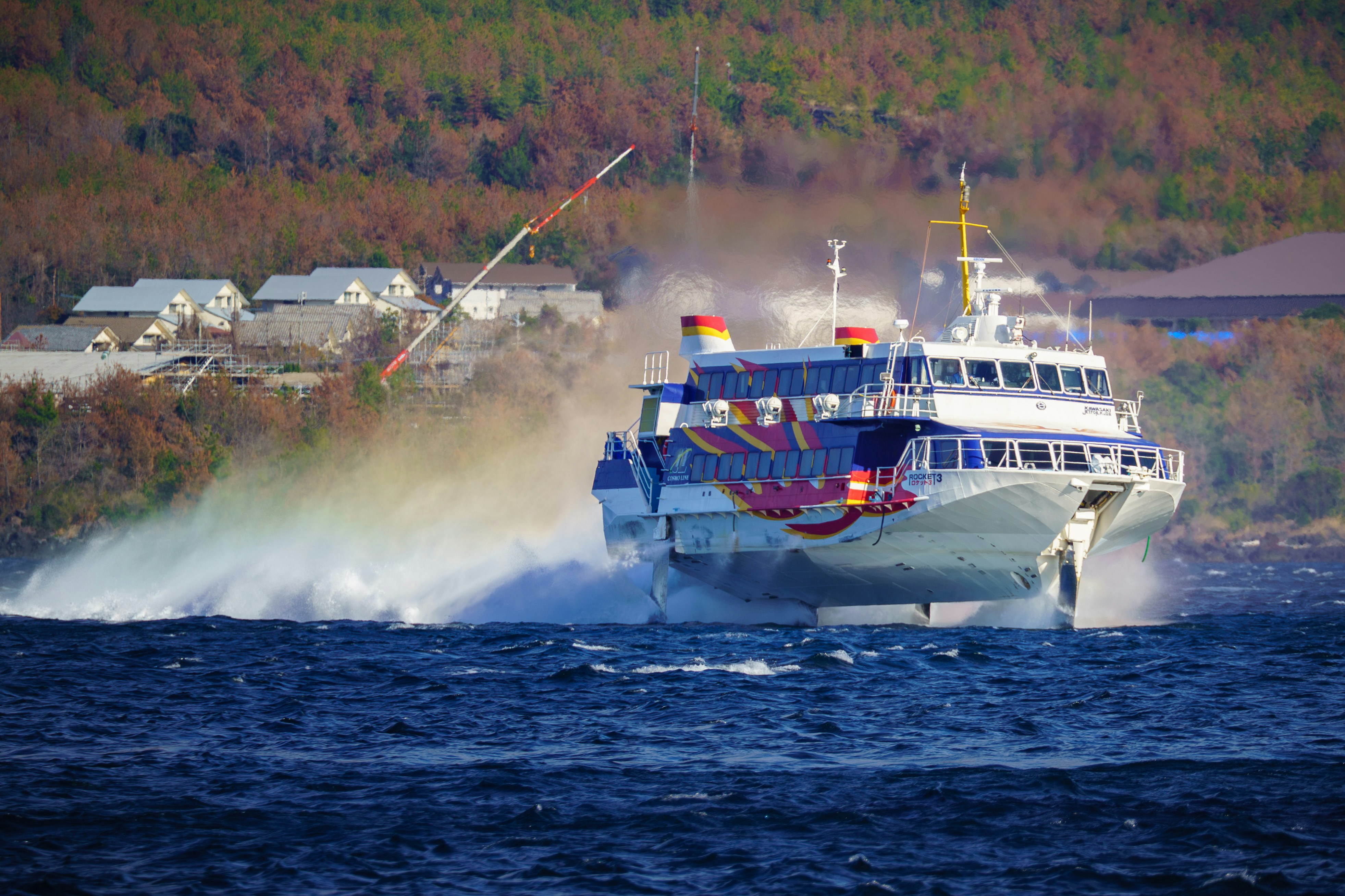 A high-speed ferry cutting through blue water.