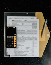 Tax forms with calculator and pen on desk