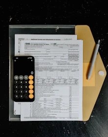 Tax forms with calculator and pen on desk