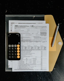 Tax forms with calculator and pen on desk