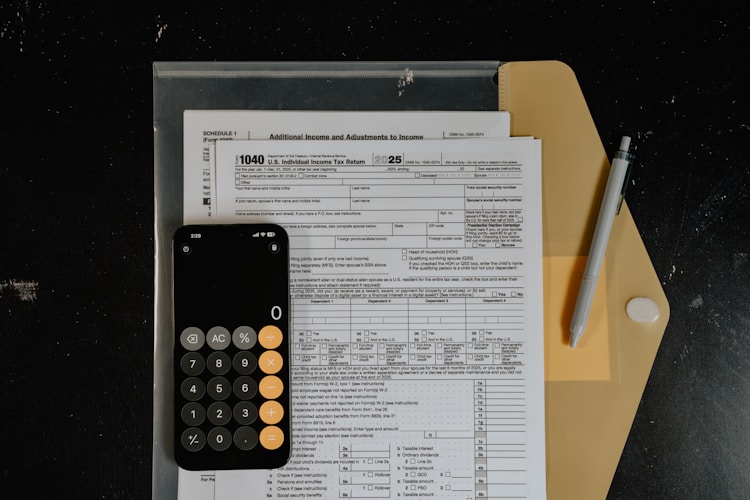 Calculator and pen resting on tax forms, representing the financial planning involved in Gold IRA management