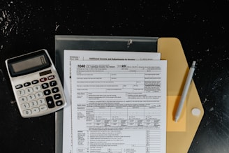 Calculator and tax forms on a dark surface.