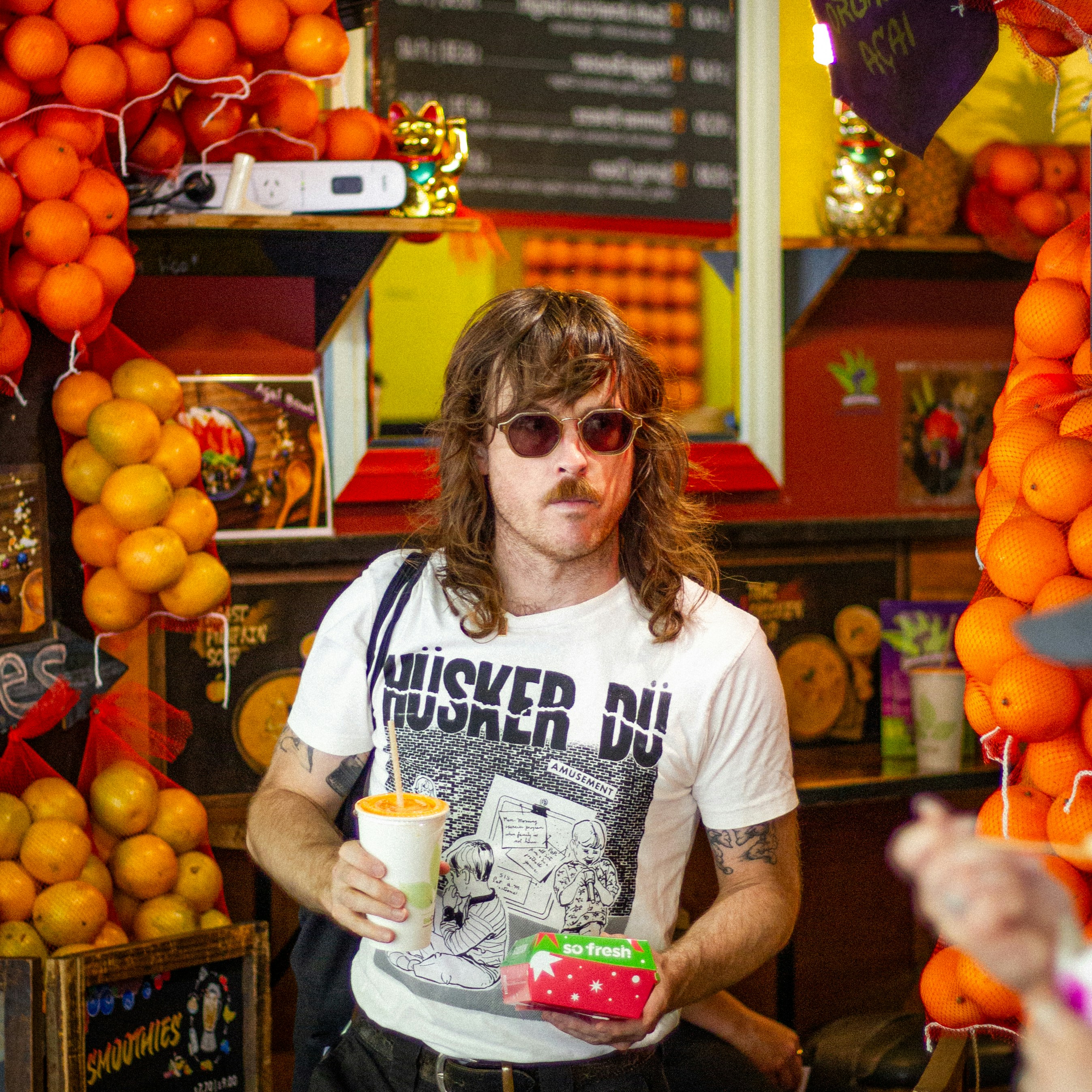 Mann mit Sonnenbrille und Vokuhr hält Getränk und Obst
