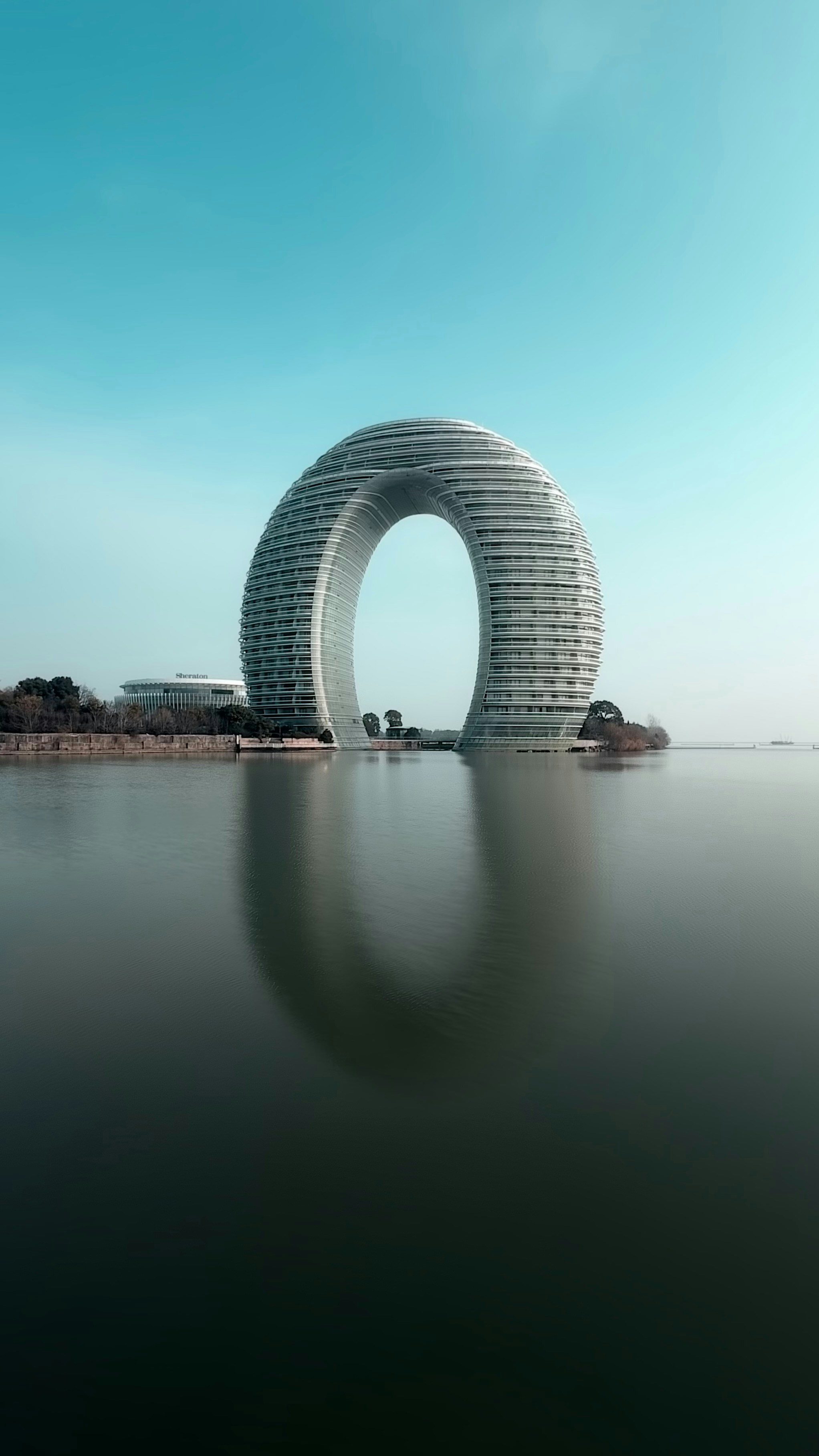 Edificio circolare unico riflesso nell'acqua sotto il cielo