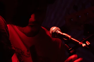 A singer performs on stage under red lights.