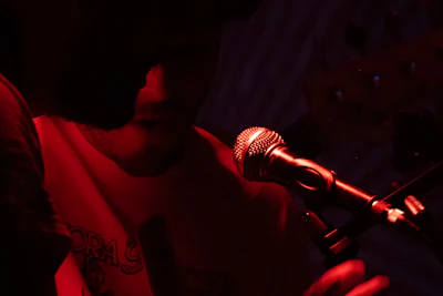 A singer performs on stage under red lights.