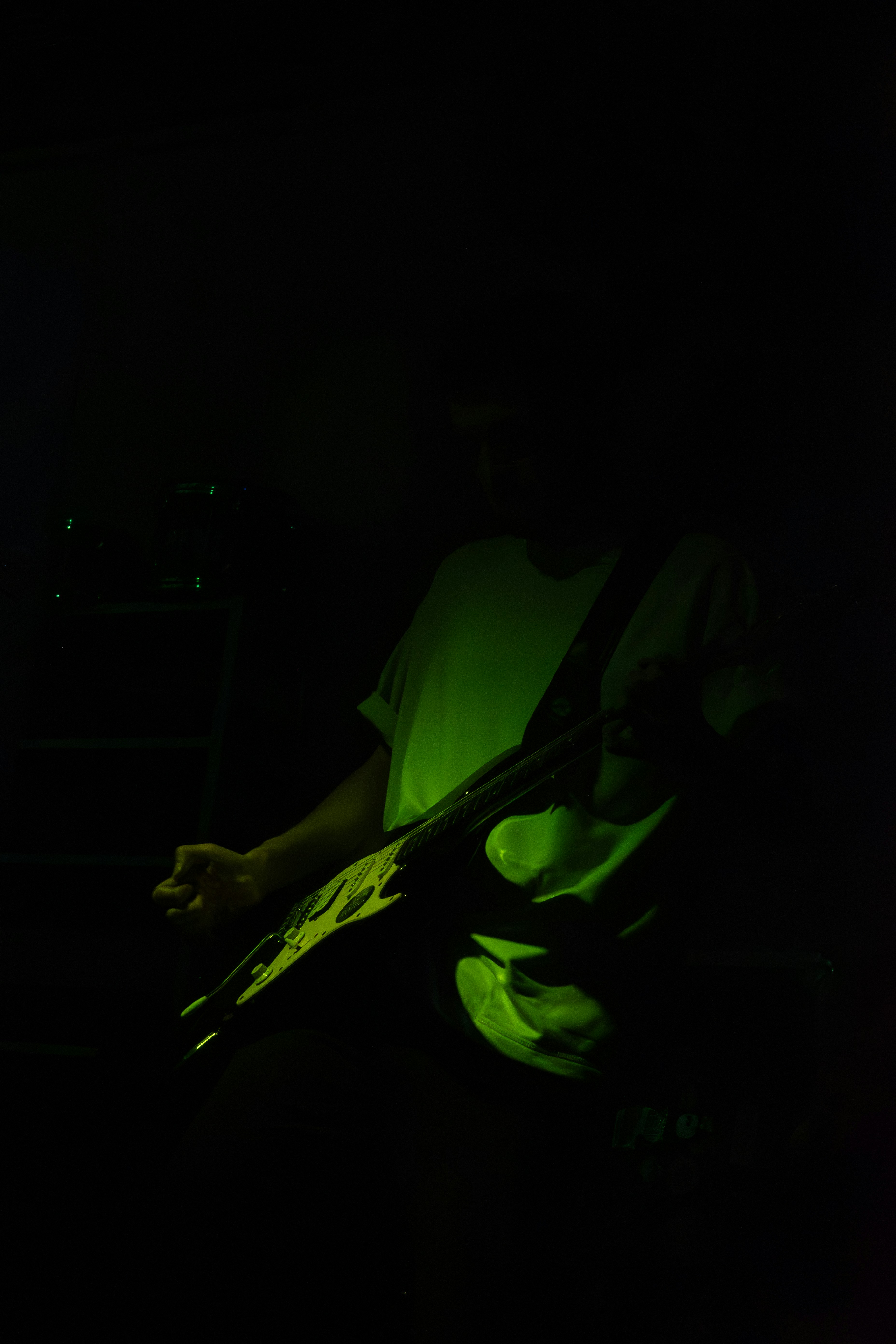 Musician playing electric guitar under green light