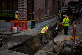 Construction workers digging a trench on a city street