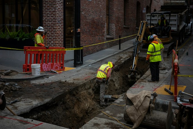Construction workers digging a trench on a city street for underground utility work