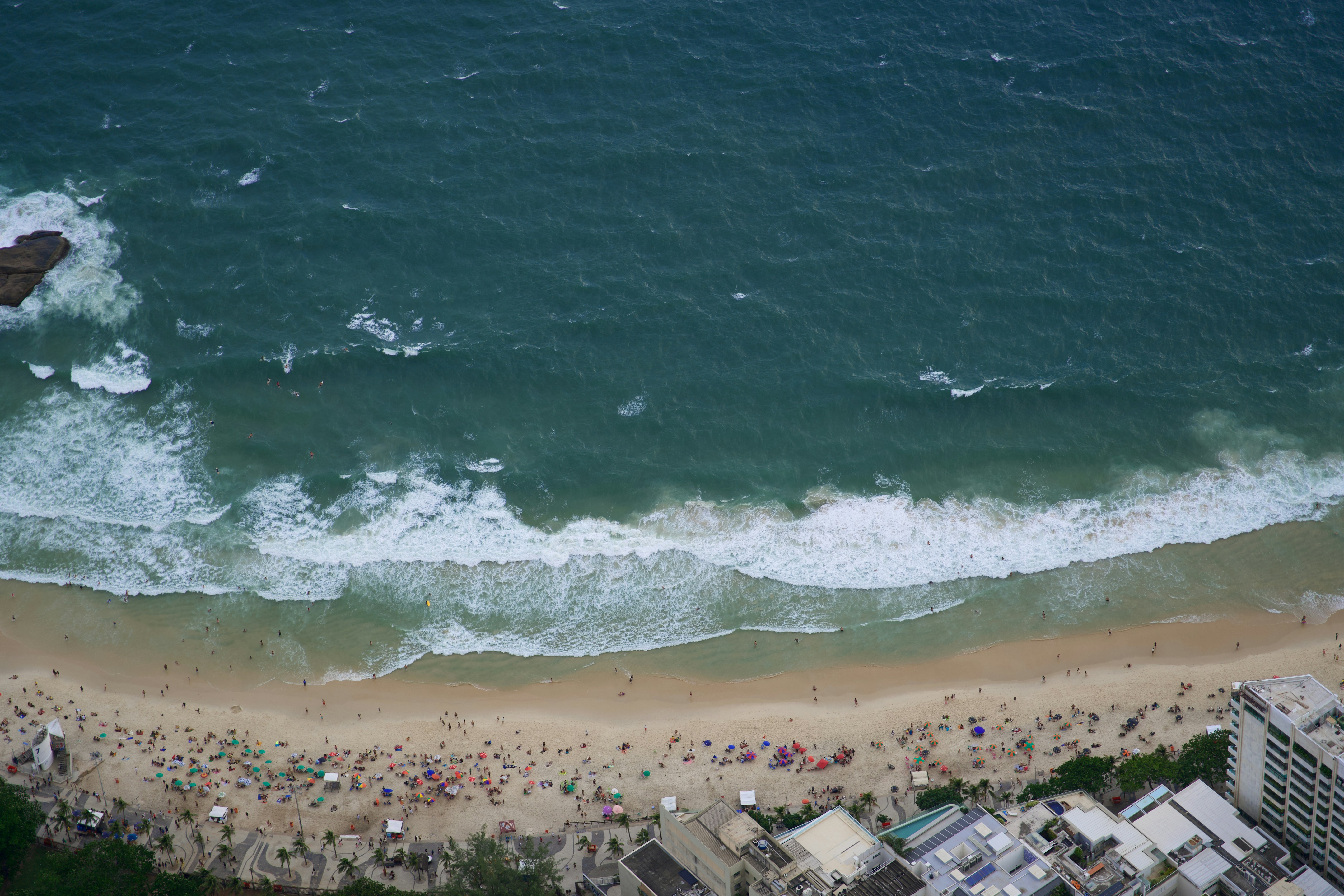Aerial view of a crowded beach with ocean waves crashing.