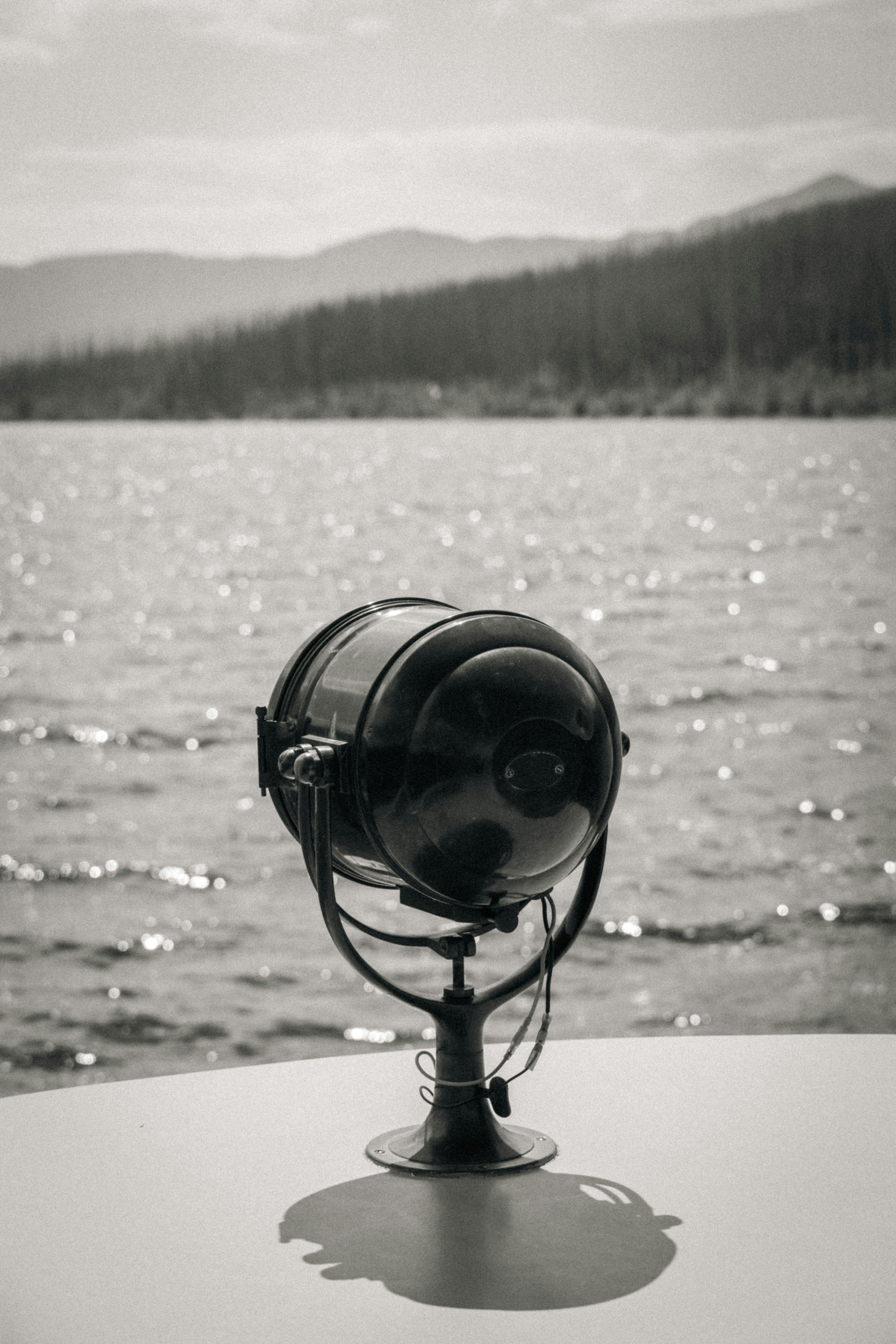 A spotlight stands on a boat deck by the water.