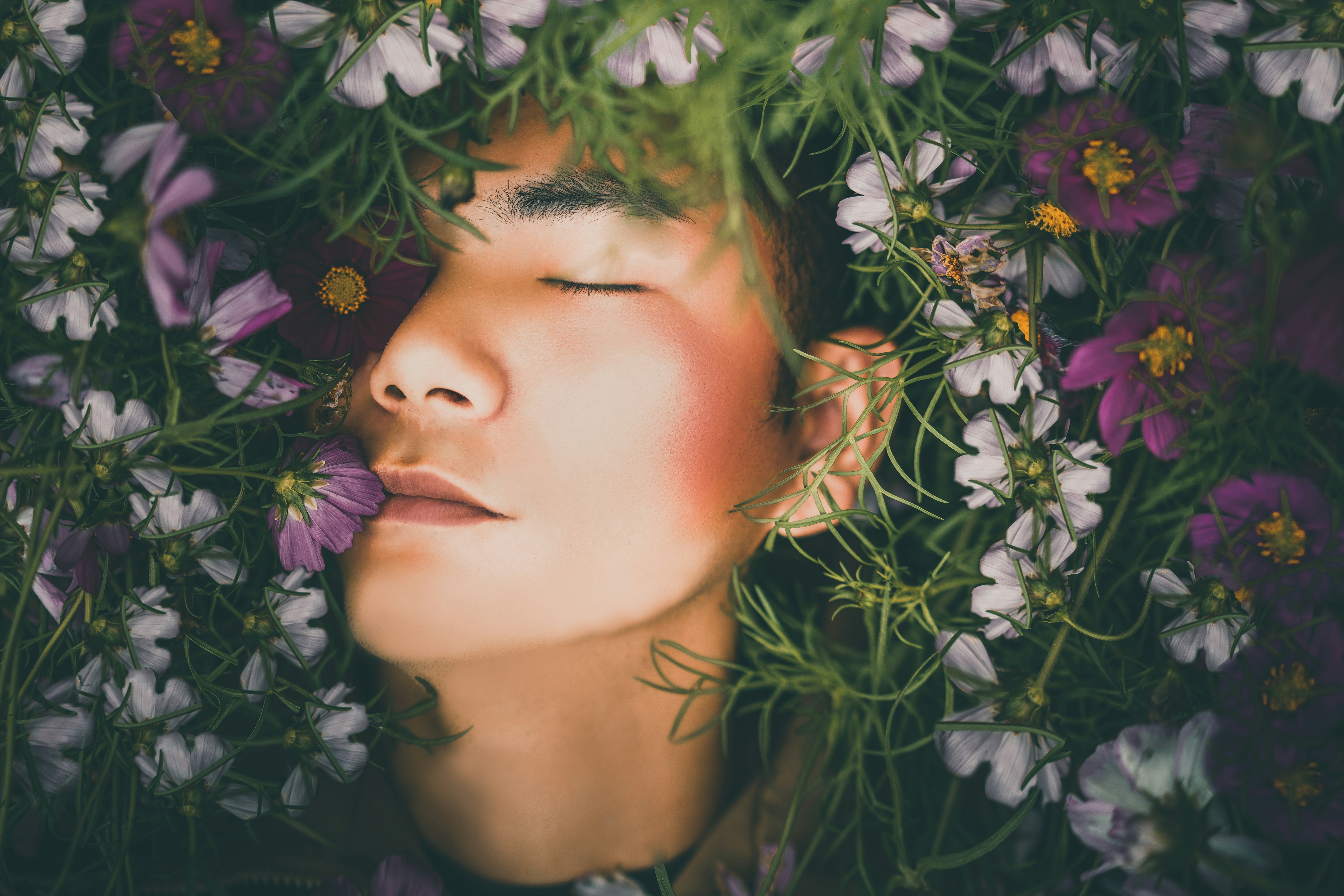 Man sleeping peacefully surrounded by flowers and greenery