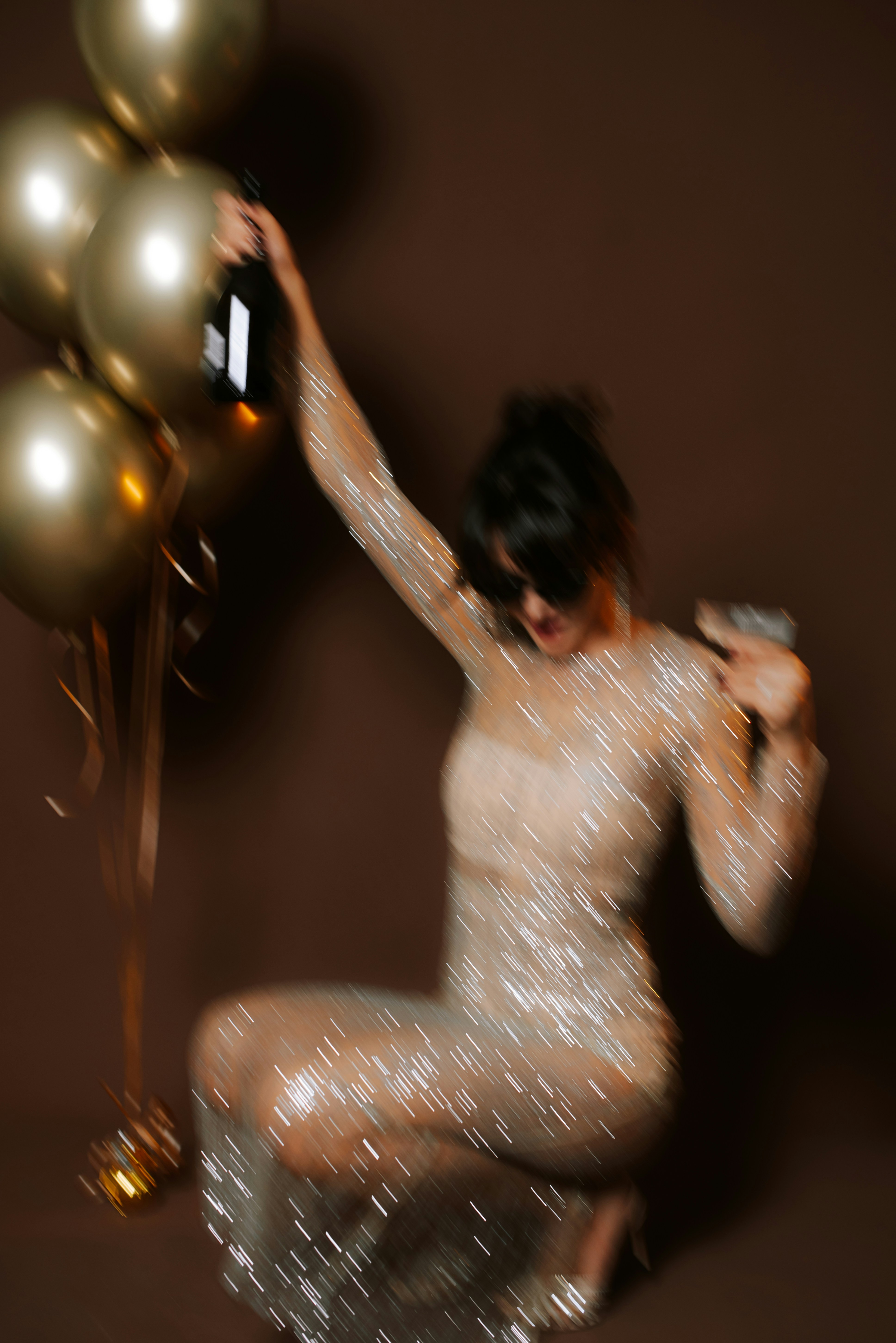 Woman in sparkly dress with balloons and champagne