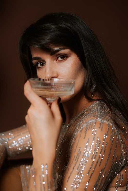 Woman in sparkling dress drinks from champagne glass