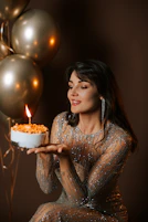 Woman in sparkly dress blowing out birthday candle